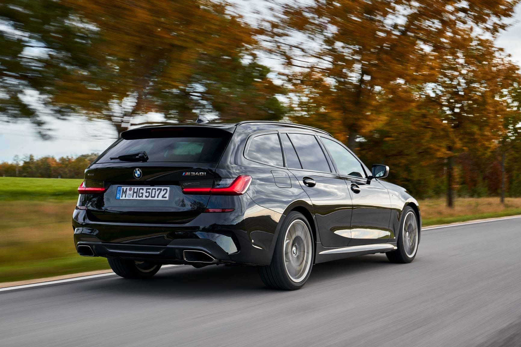 A rolling rear three quarters shot of the new BMW M340i Touring in black.
