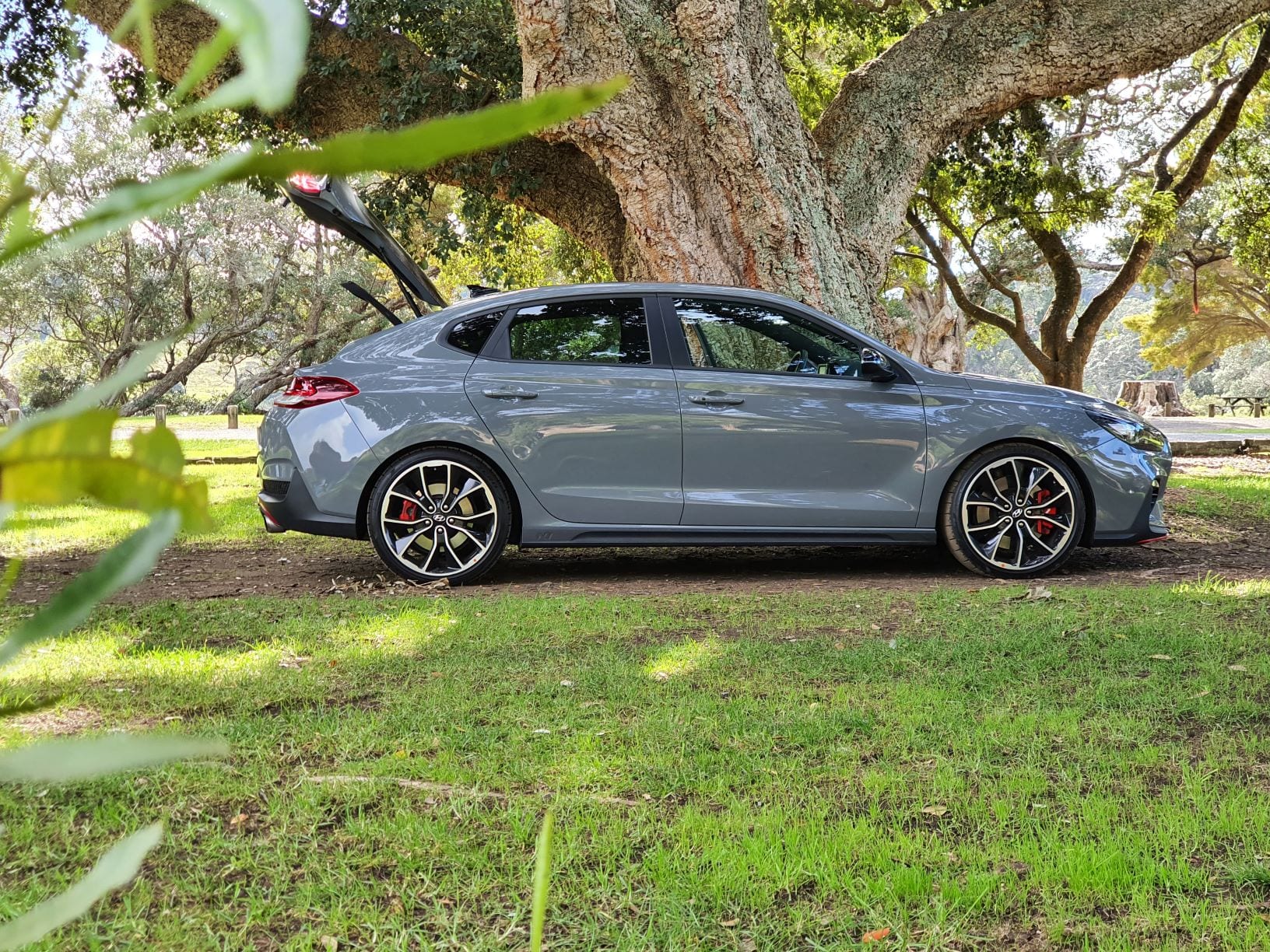 The Hyundai i30 N Fastback with the bootlid raised. Parked in a grassy area.