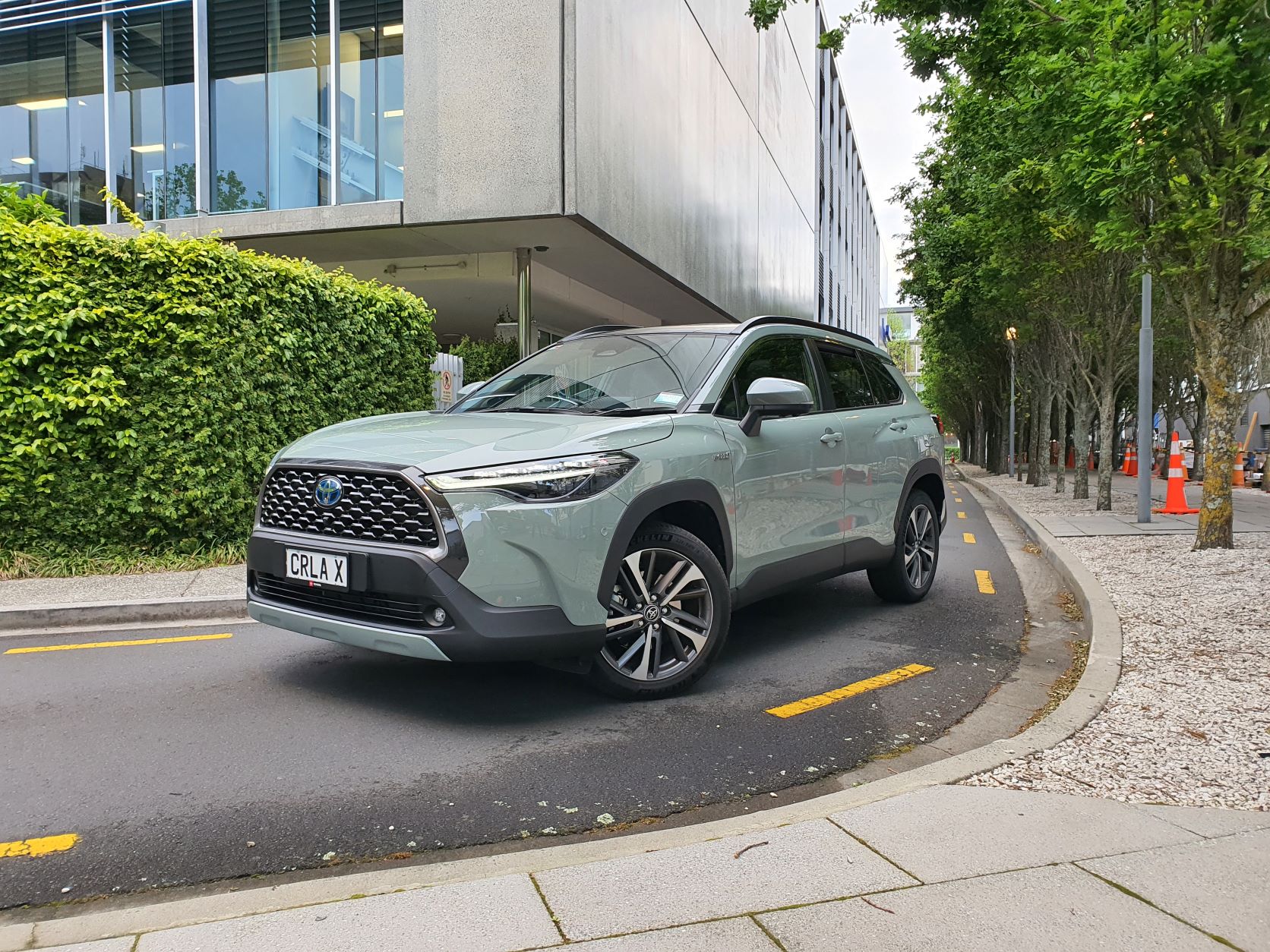 Front three quarters view of a 2022 Toyota Corolla Cross Limited Hybrid E-Four AWD in an urban environment
