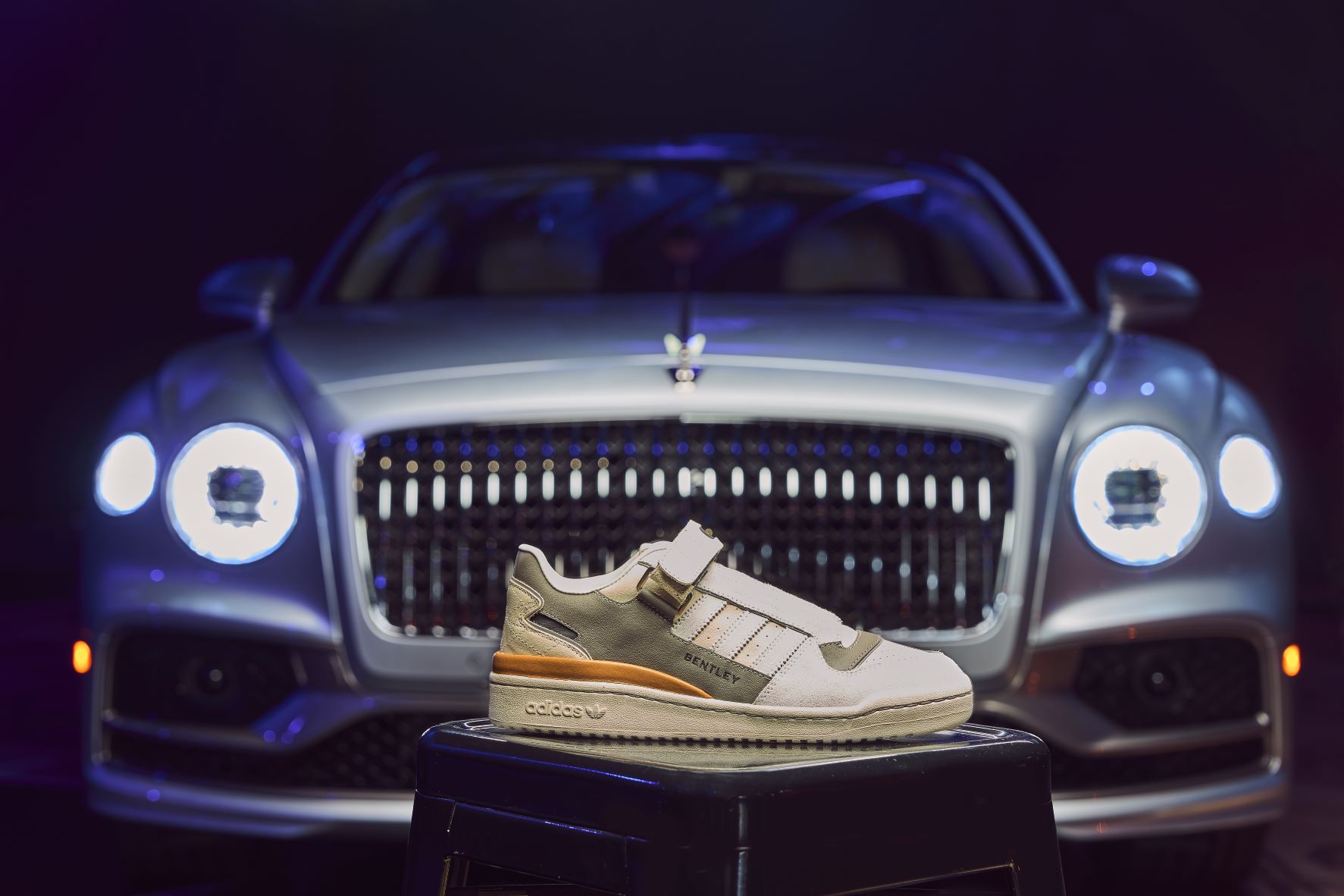 Bentley x The Surgeon Adidas Forum Low sneakers in front of a Bentley Flying Spur sedan.