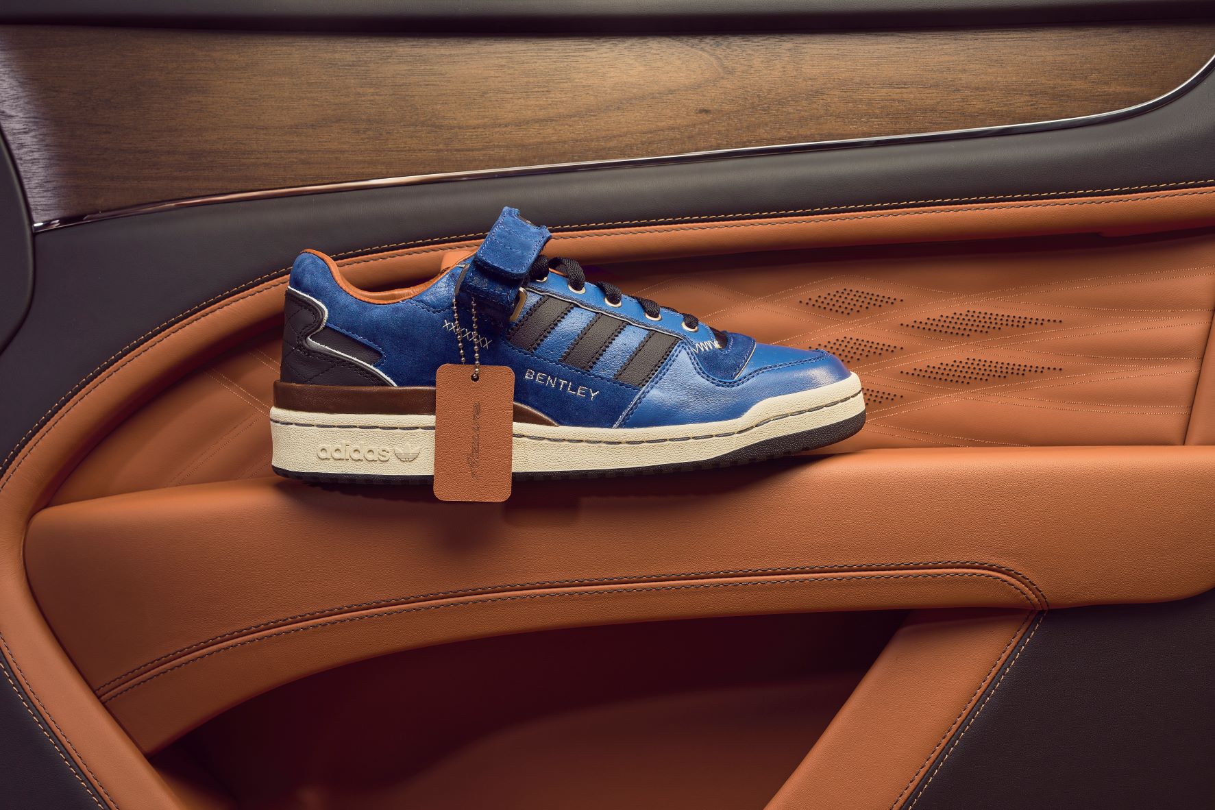 Bentley x The Surgeon Adidas Forum Low sneakers on the door armrest of a Bentley car.