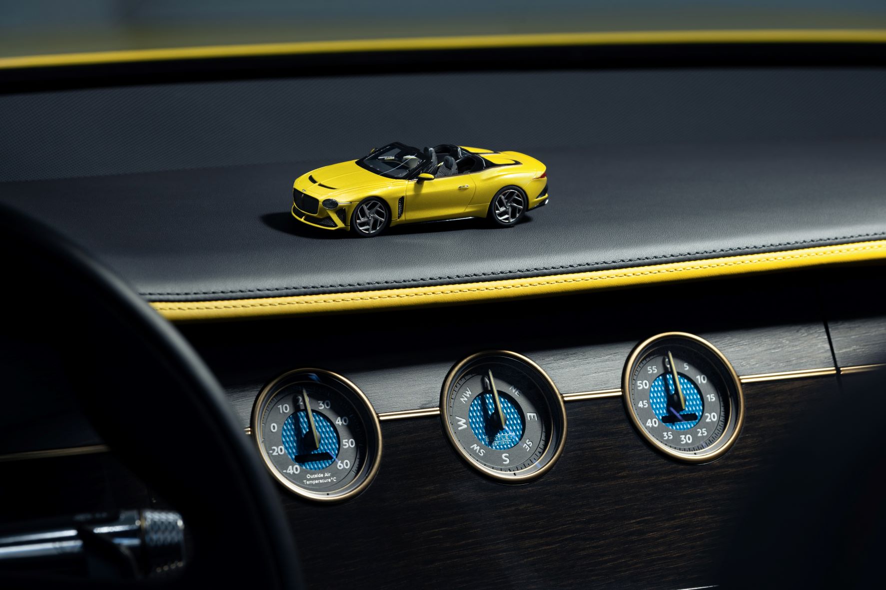 A Yellow Flame Bentley Mulliner Bacalar sitting atop the dashboard of a real Bentley Mulliner Bacalar in the same specification.