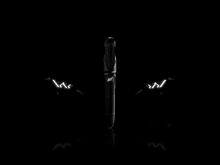 A promotional photo of a Lamborghini Montegrappa pen in front of a Lamborghini Huracan