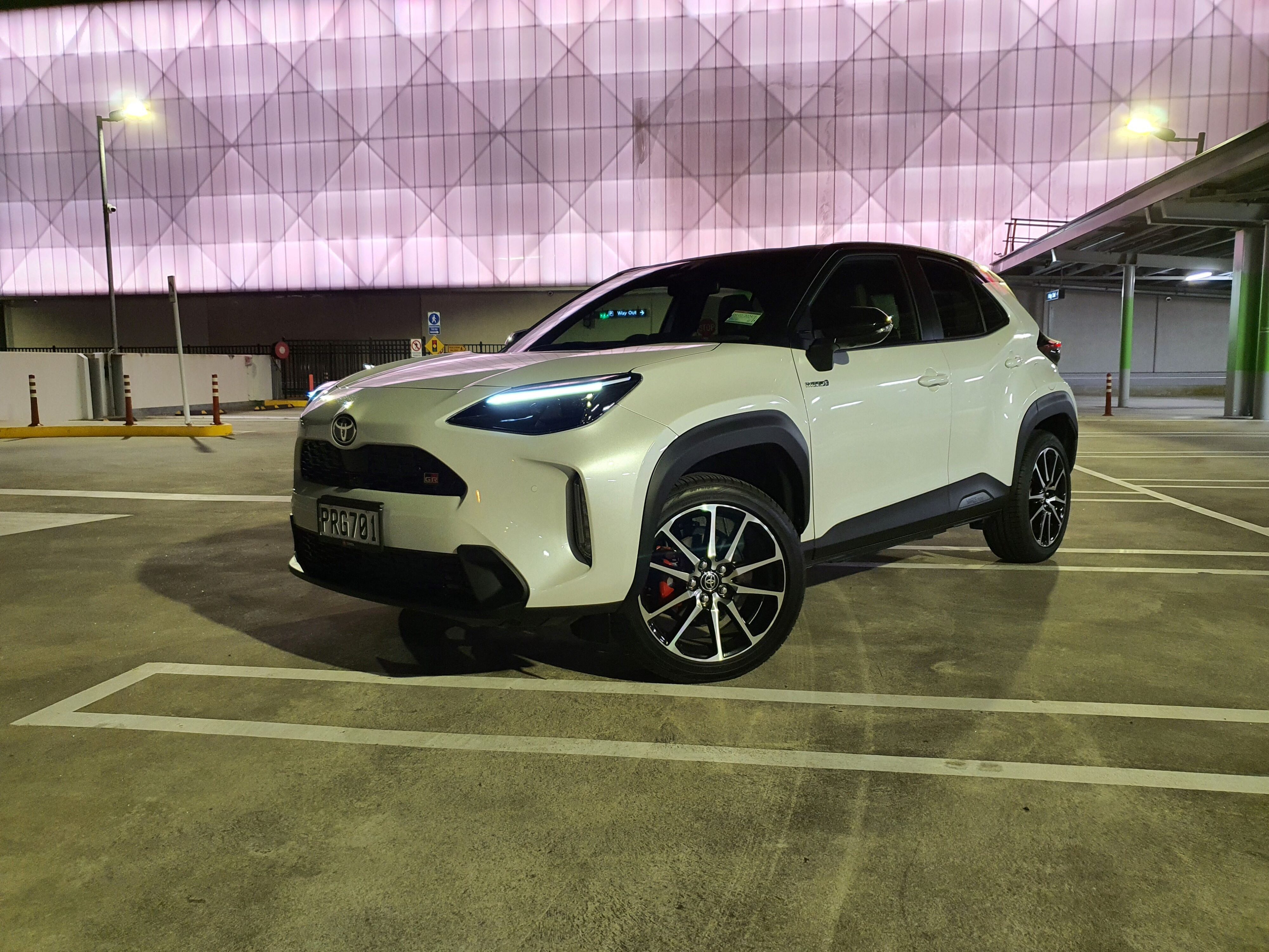 Front three quarters view of a 2023 Toyota Yaris Cross GR Sport in a white and black colour scheme on the rooftop of a mall.