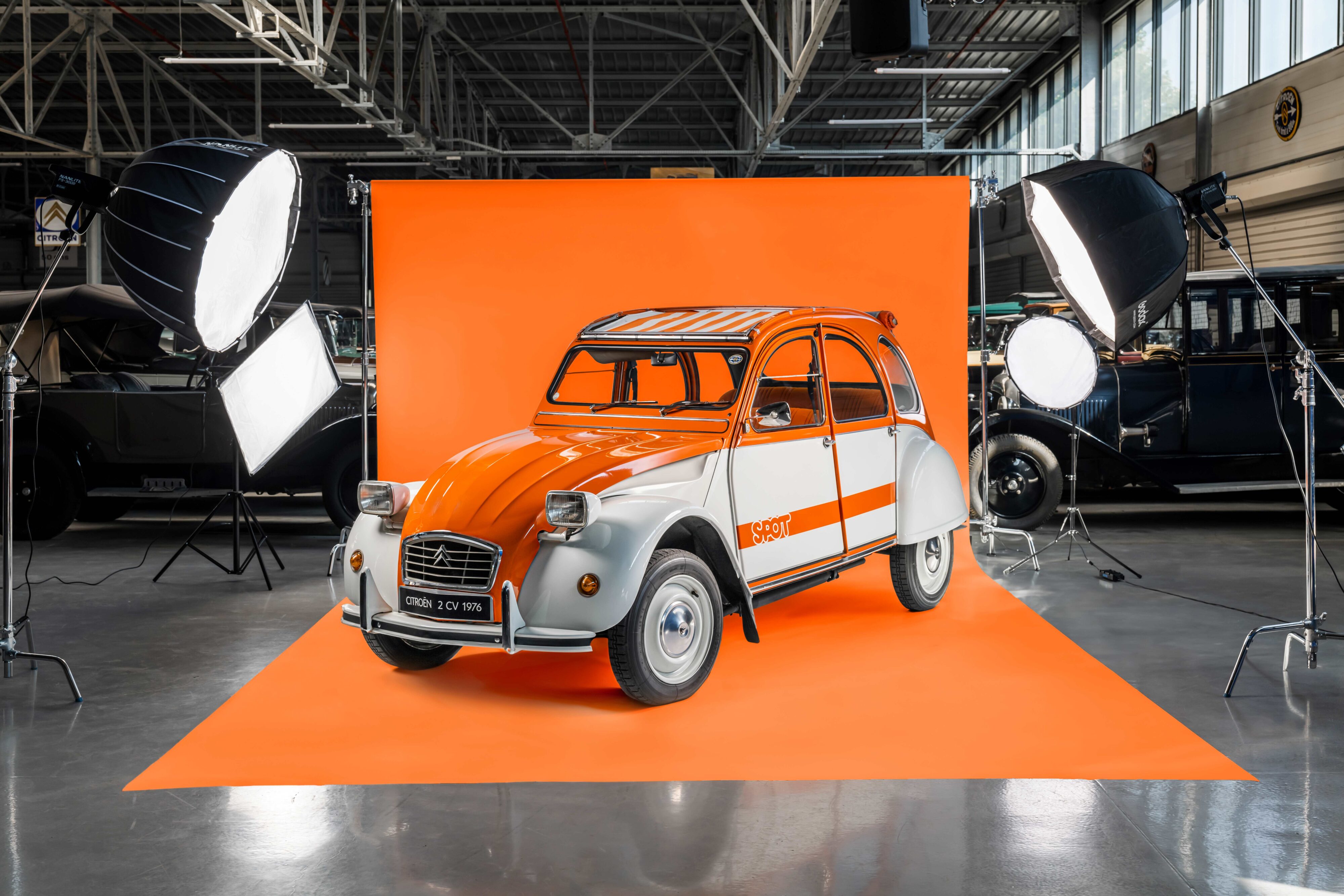 A photo of a 1976 Citroen 2CV Spot Special Edition on an orange screen background.