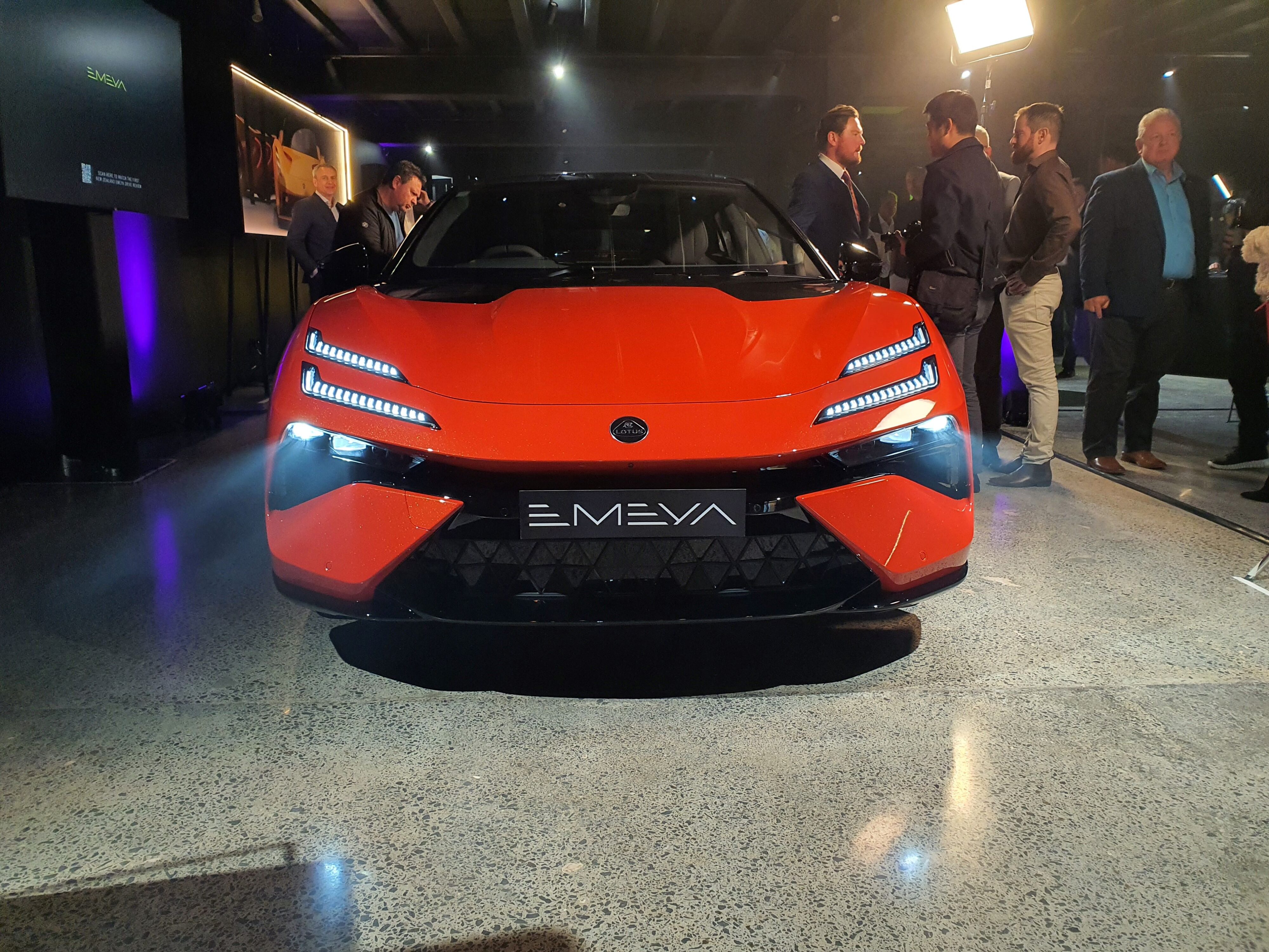 Front on view of a 2024 Lotus Emeya S in Hyperglow Orange at Lotus Auckland.