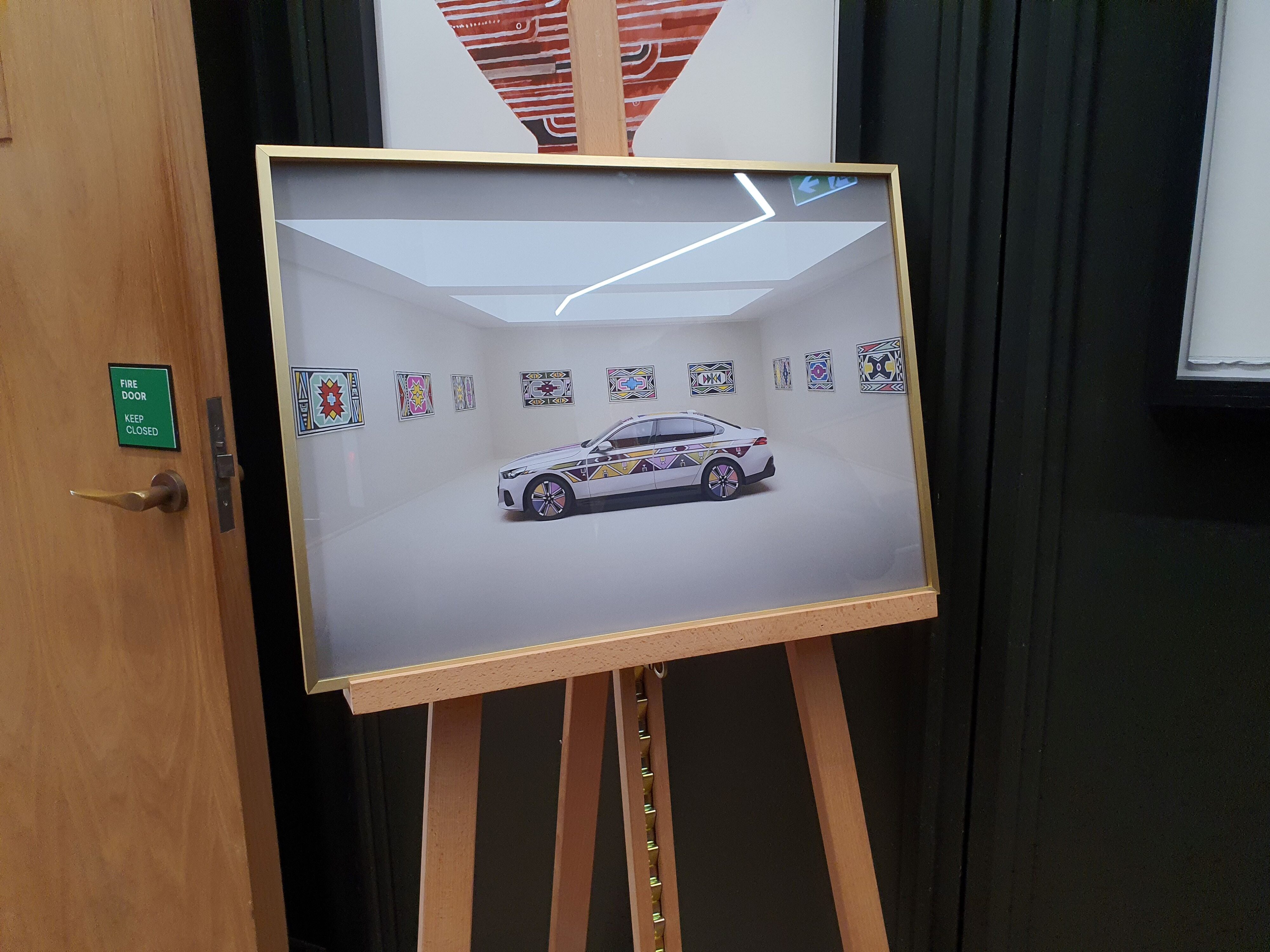 A framed print of a BMW i5 Flow Nostokana on an easel in The Hotel Britomart.