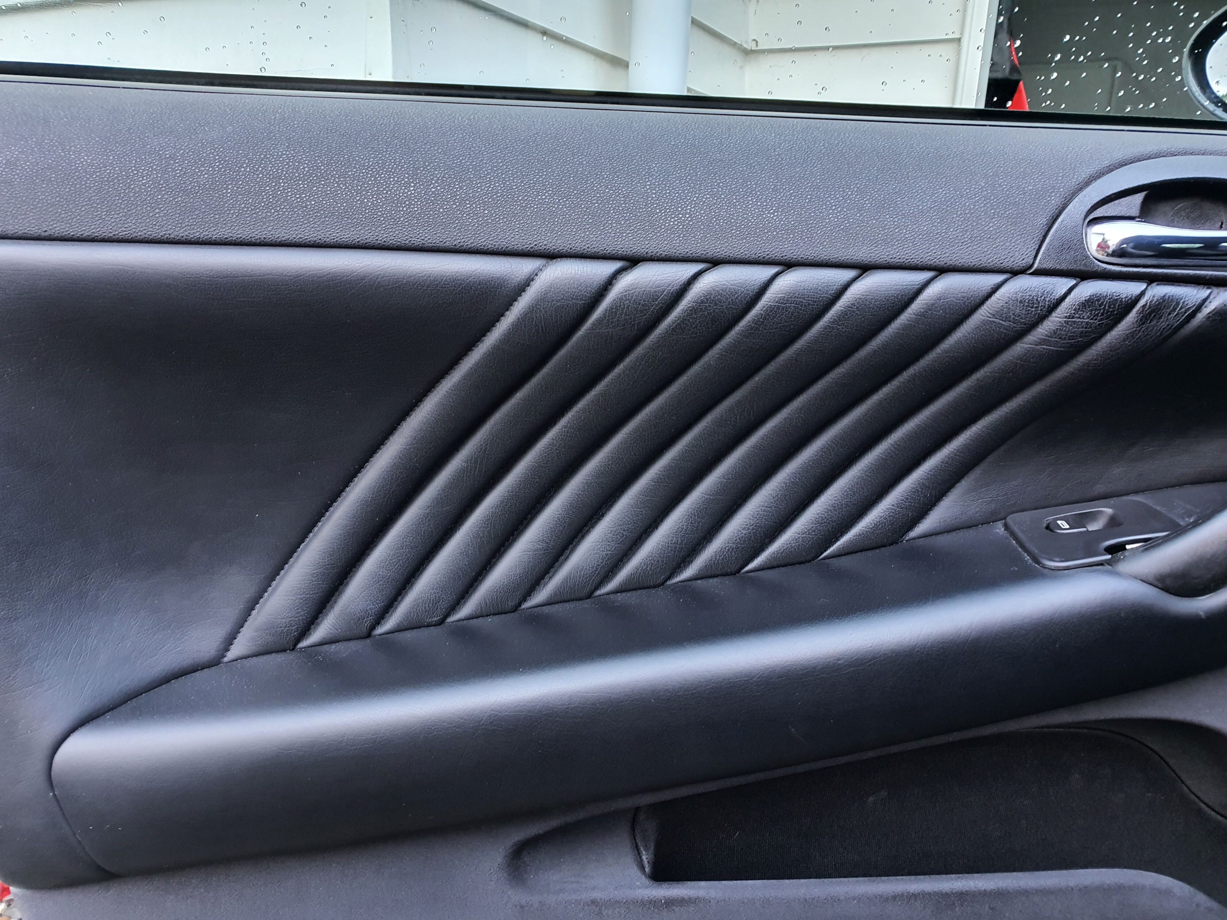 A photo of the left front door card on a 2004 Alfa Romeo 147 GTA after using Armor All's new Leather Protectant.