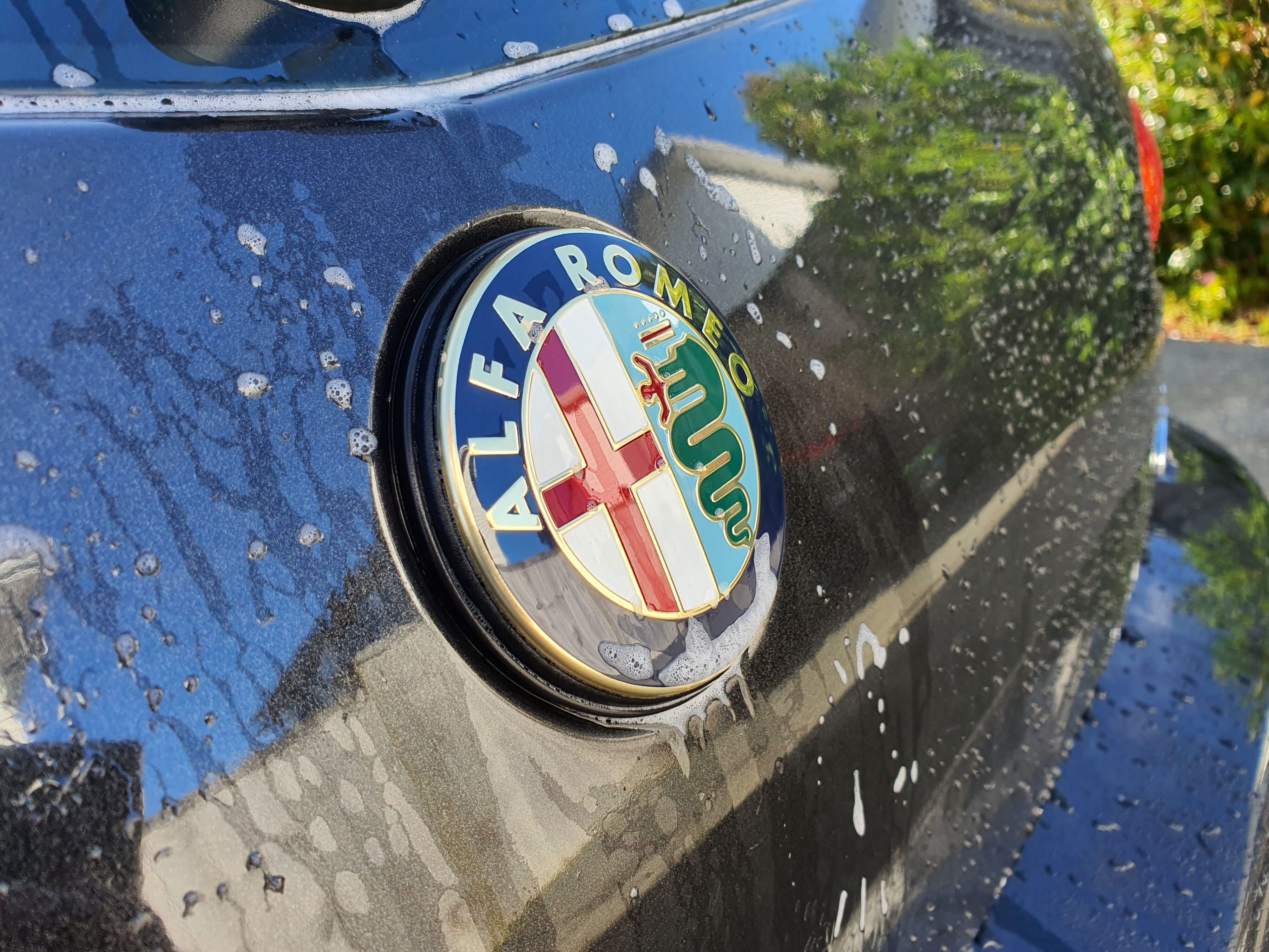 A photo of the rear Alfa Romeo badge on a 147 GTA surrounded by foaming water during a wash with Armor All's new Wash & Wax solution.
