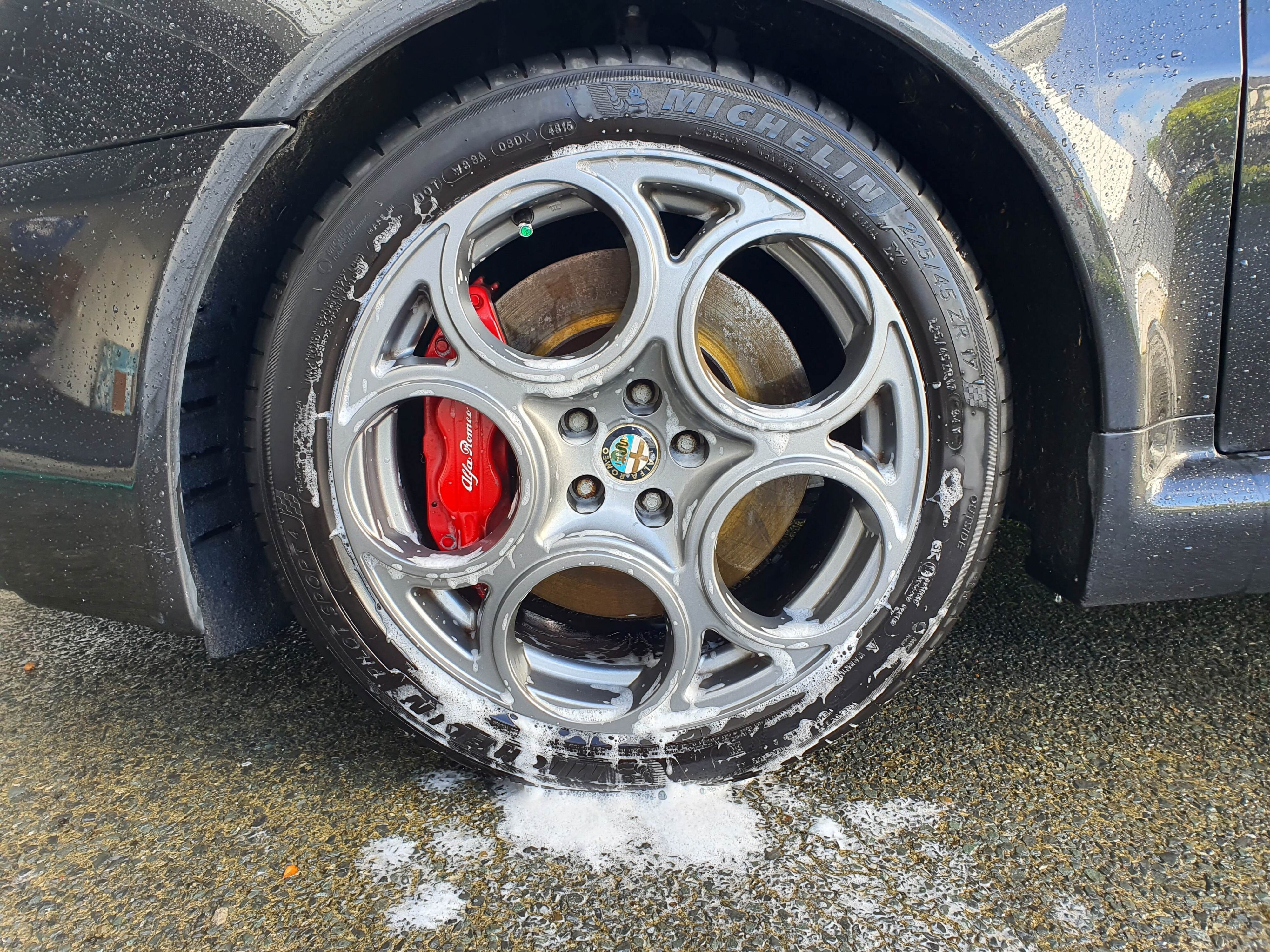A photo of a front left wheel of a 2004 Alfa Romeo 147 GTA covered in foam from Armor All's new Wash & Wax solution.