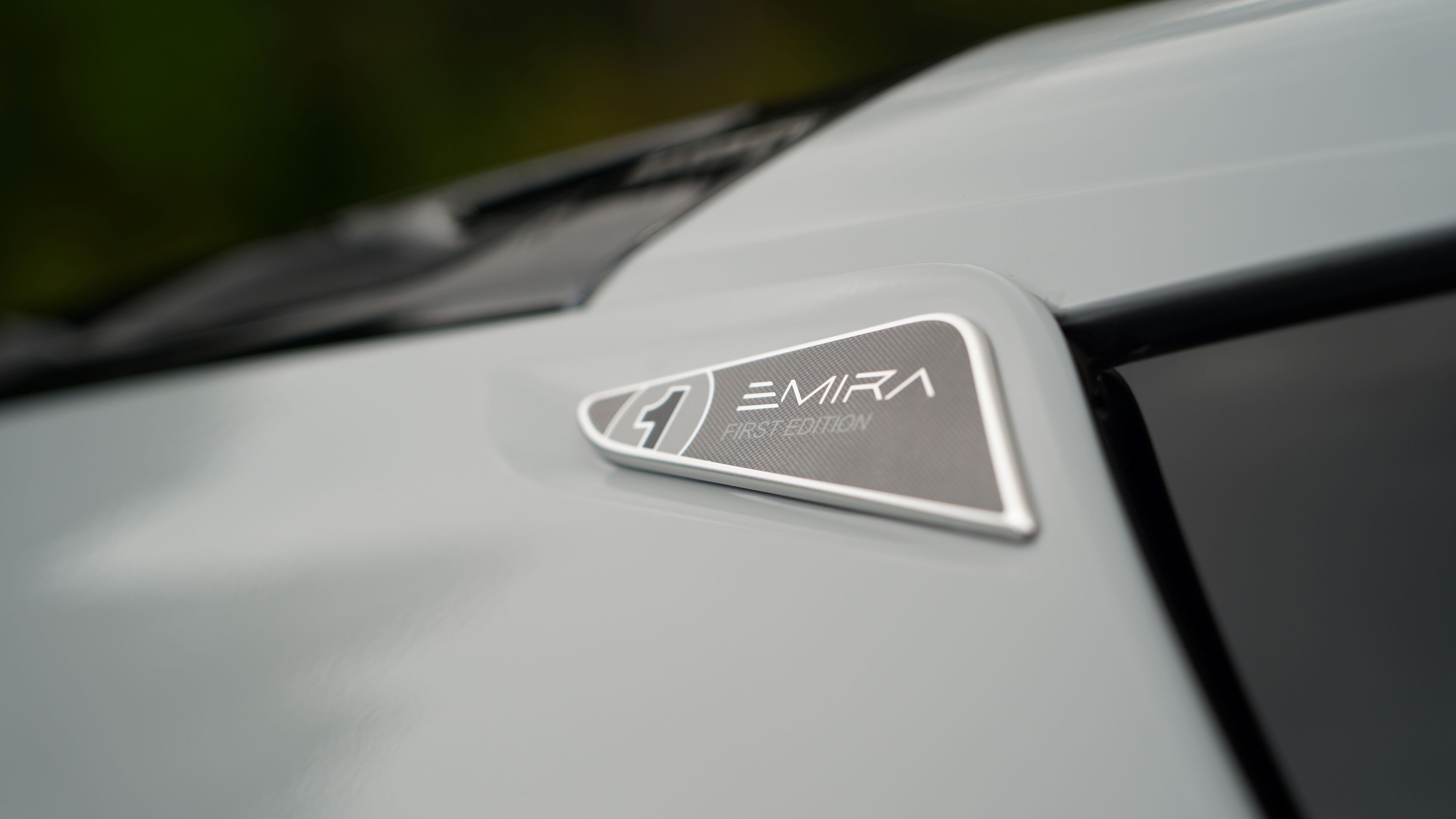 'Emira First Edition' badging on the rear pillar of a 2024 Lotus Emira i4 Turbo in Nimbus Grey.