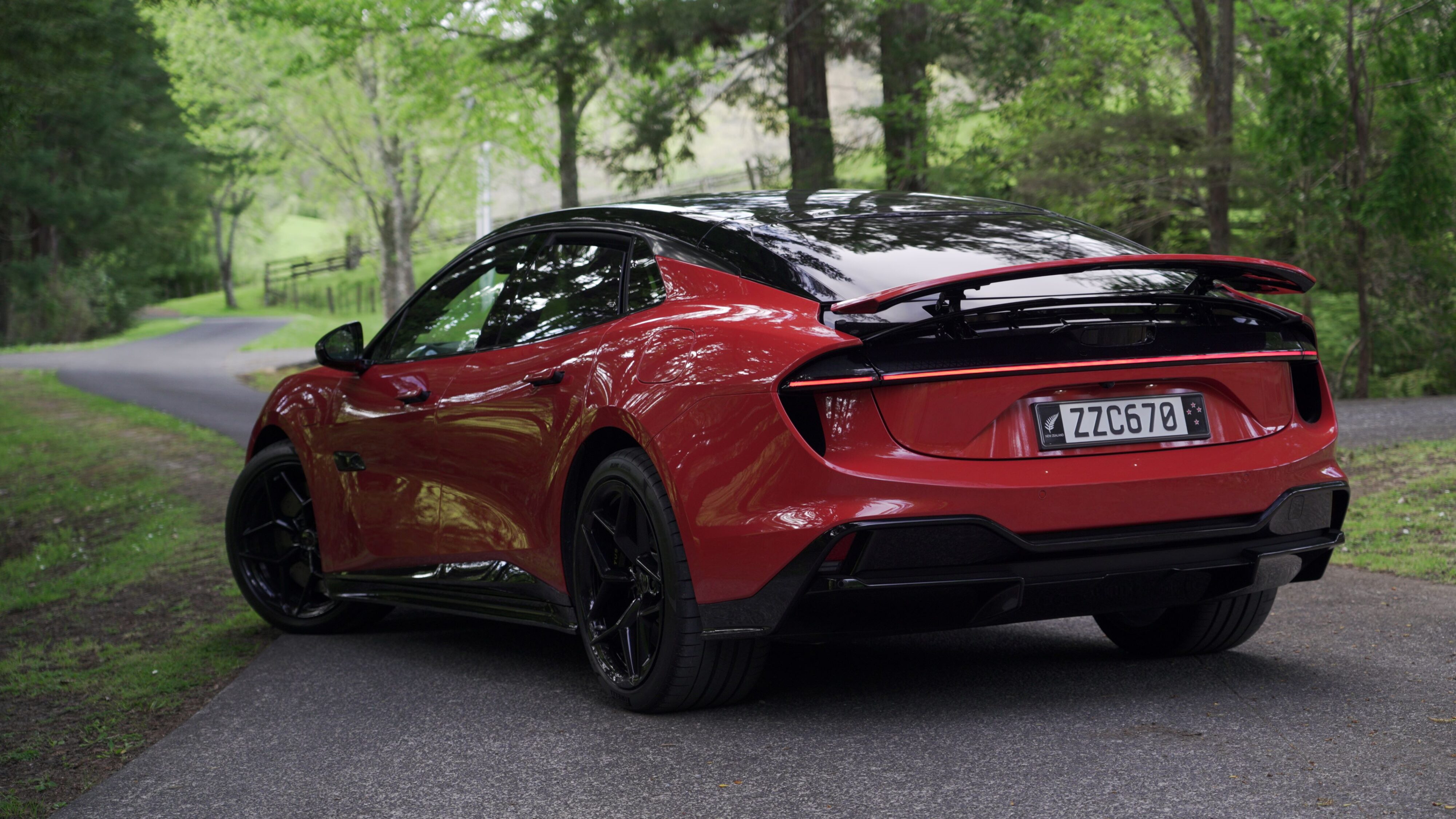 Rear three quarters view of a 2024 Lotus Emeya S in Fireglow Orange.