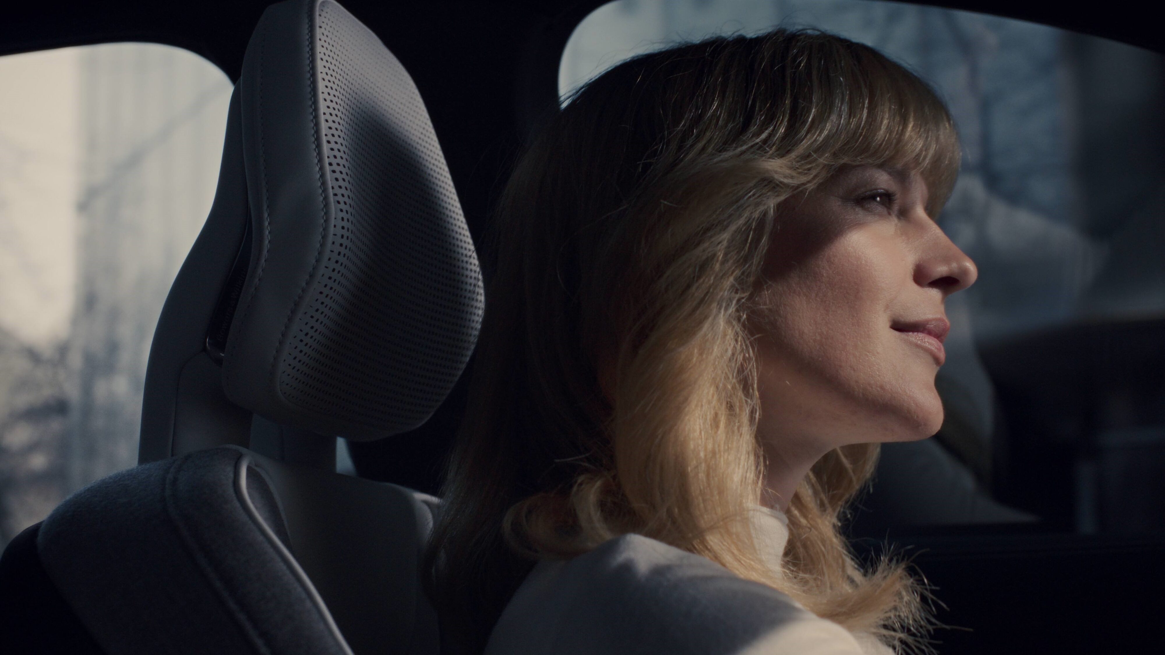 A photograph of a happy woman behind the wheel of a new Volvo EX90, the image is meant to convey the brand's driver understanding system in action.