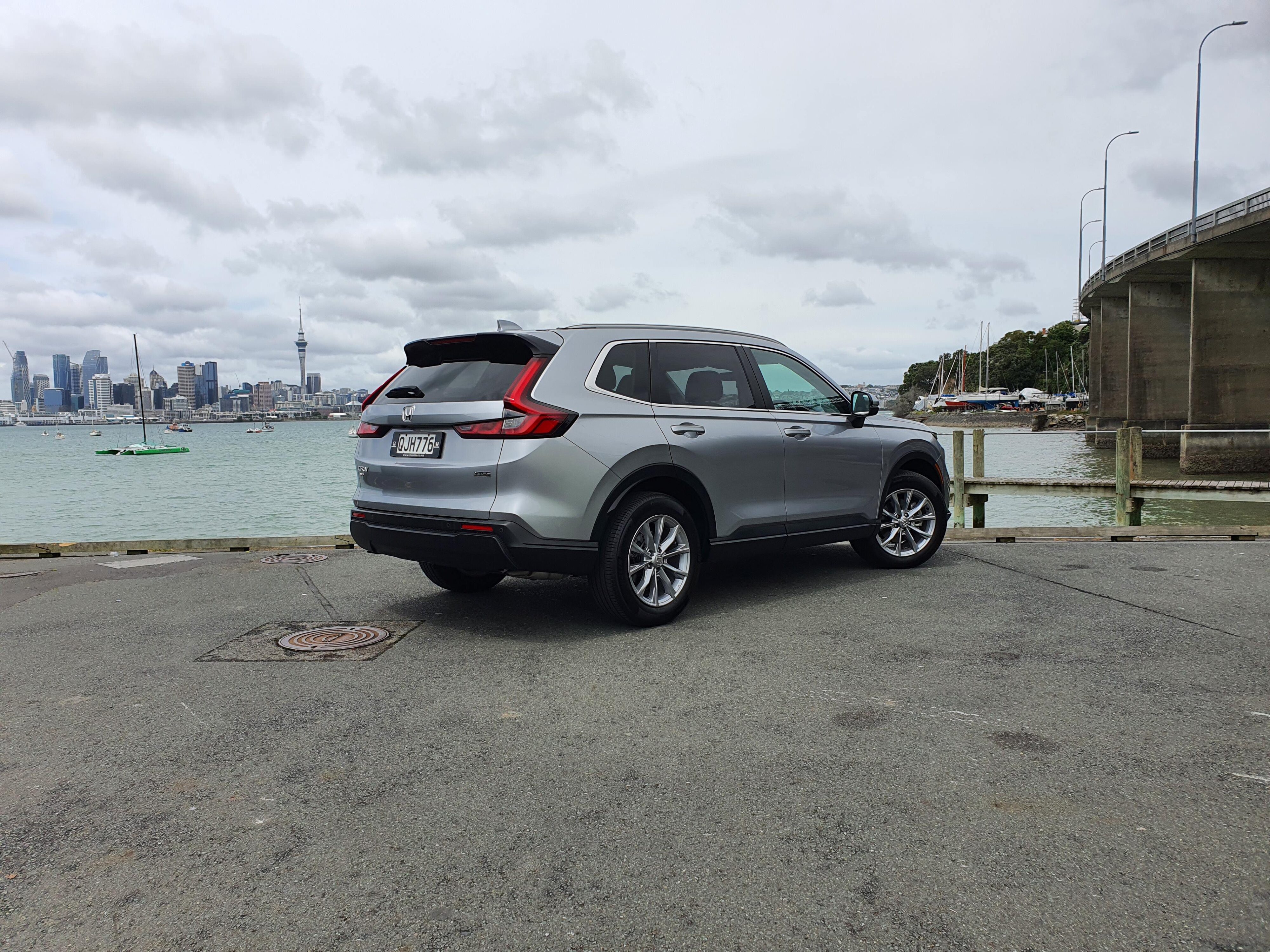 Rear three quarters view of a 2024 Honda CR-V in Silver with Auckland city in the background.