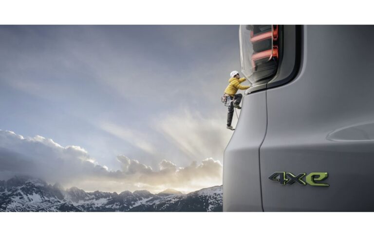 A Jeep Avenger 4xe with a mountaineer scaling the vehicle, dressed in gear from The North Face.