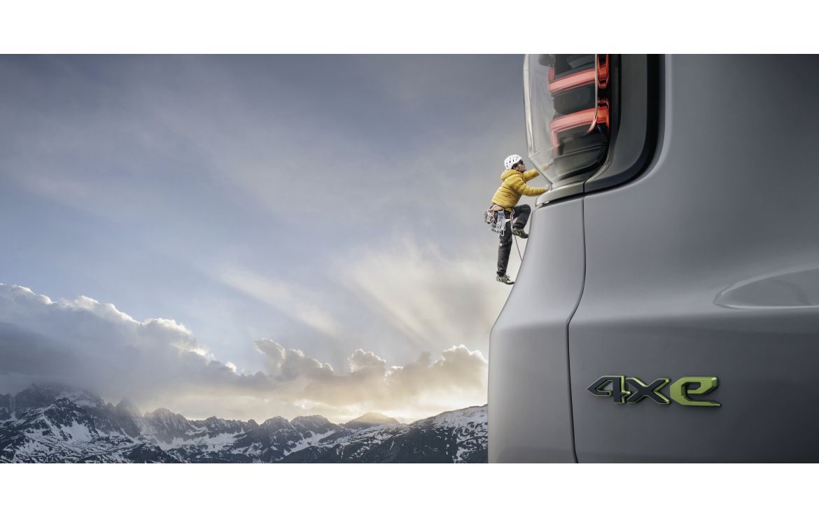 A Jeep Avenger 4xe with a mountaineer scaling the vehicle, dressed in gear from The North Face.