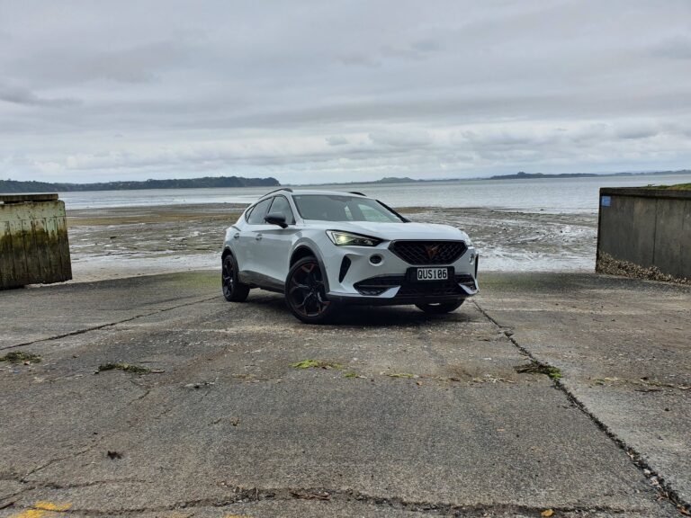 Front three quarters view of a 2024 Cupra Formentor V e-Hybrid on a boat ramp with a gloomy ocean background.
