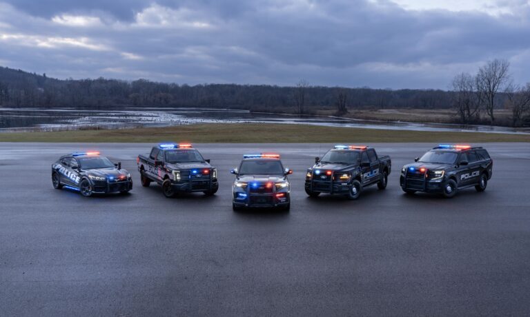 A fleet of Ford USA Police vehicles with blue and red lights on.