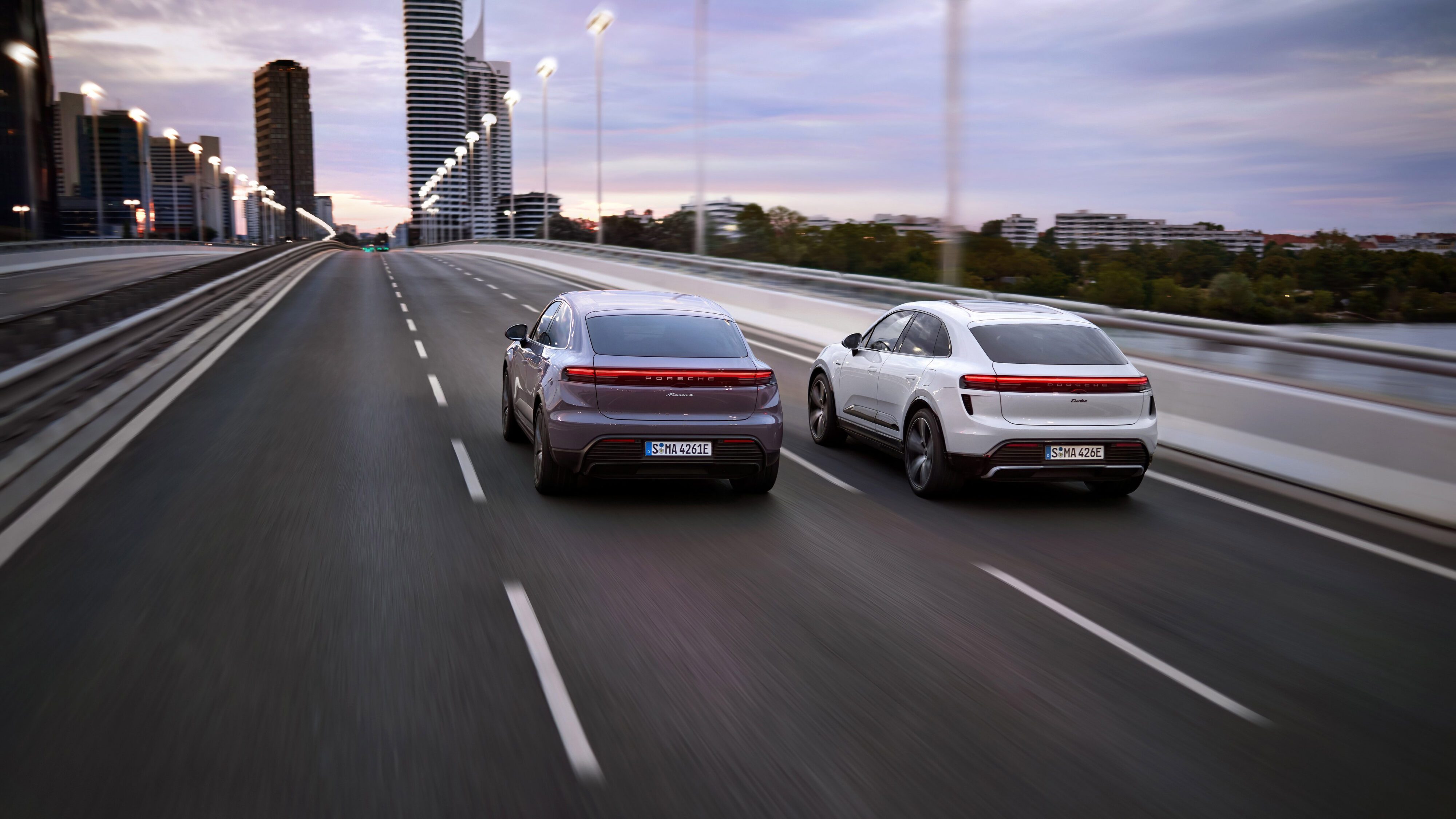 A photo of two fully electric Porsche Macans driving down a motorway.
