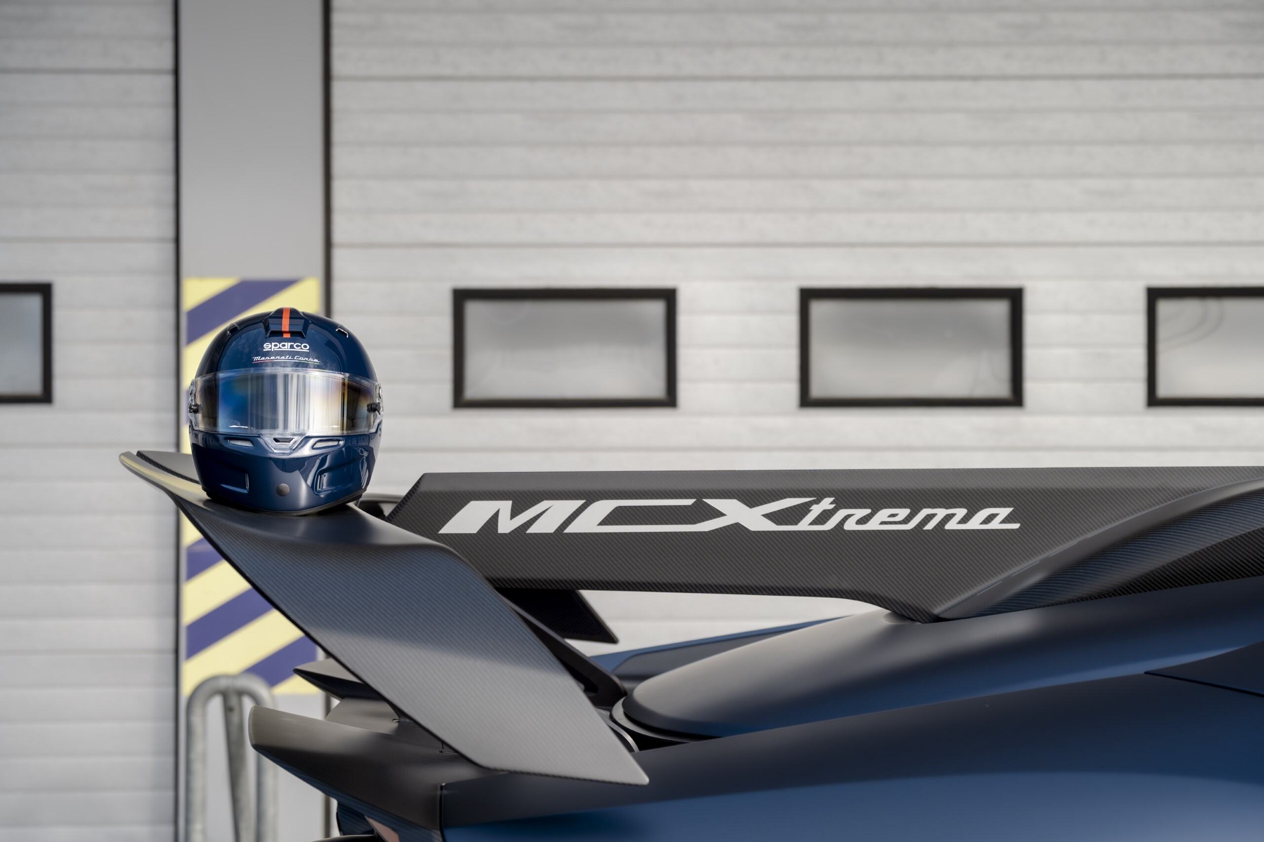 A Maserati Sparco racing helmet on the spoiler of a Maserati MCXtrema racecar.