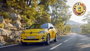 Front three quarters view of a 2025 Renault 5 in Yellow with the watermarked European Car of the Year 2025 award in the top right.