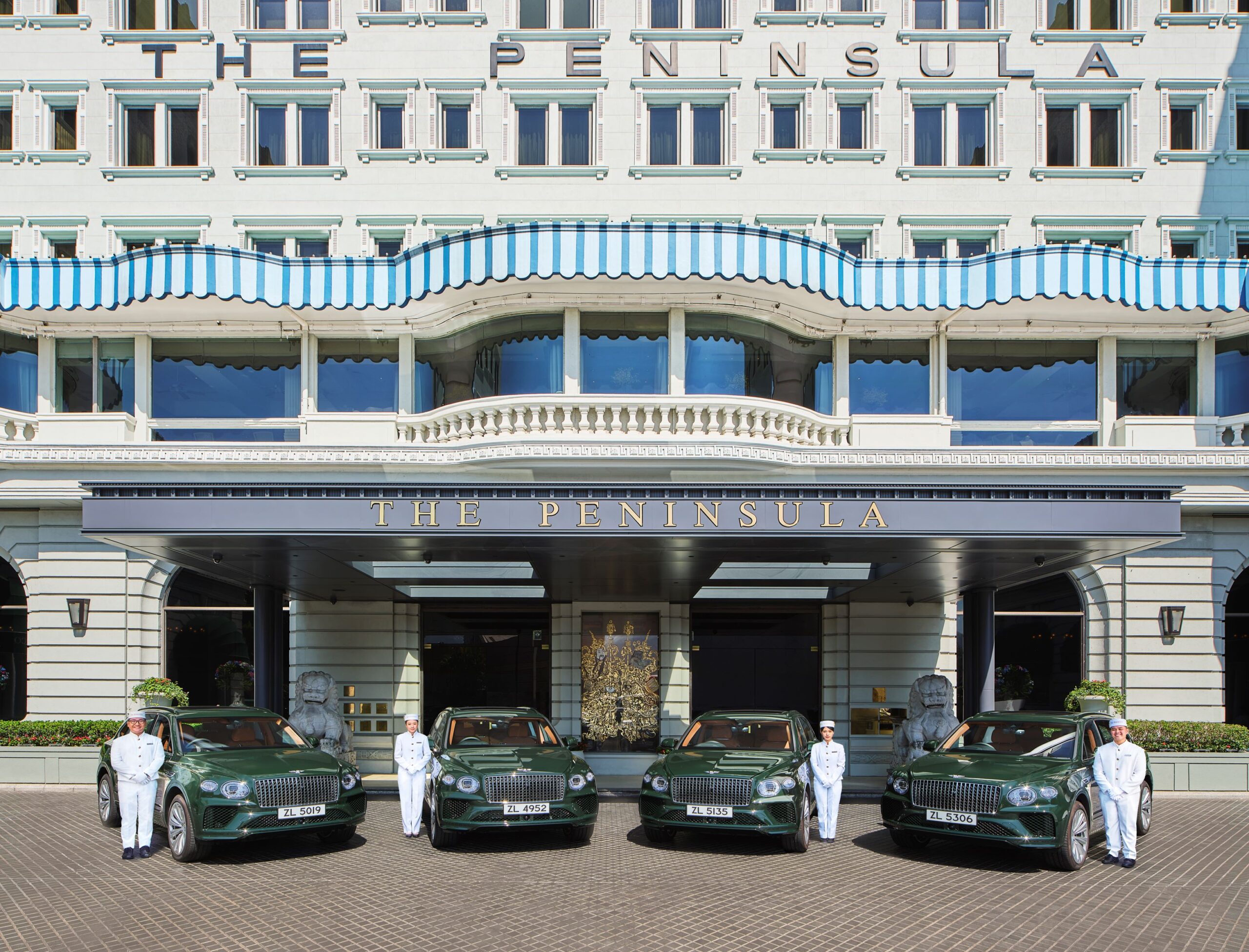 Four dark green Bentley Bentayga EWBs parked in front of The Peninsula Hong Kong.