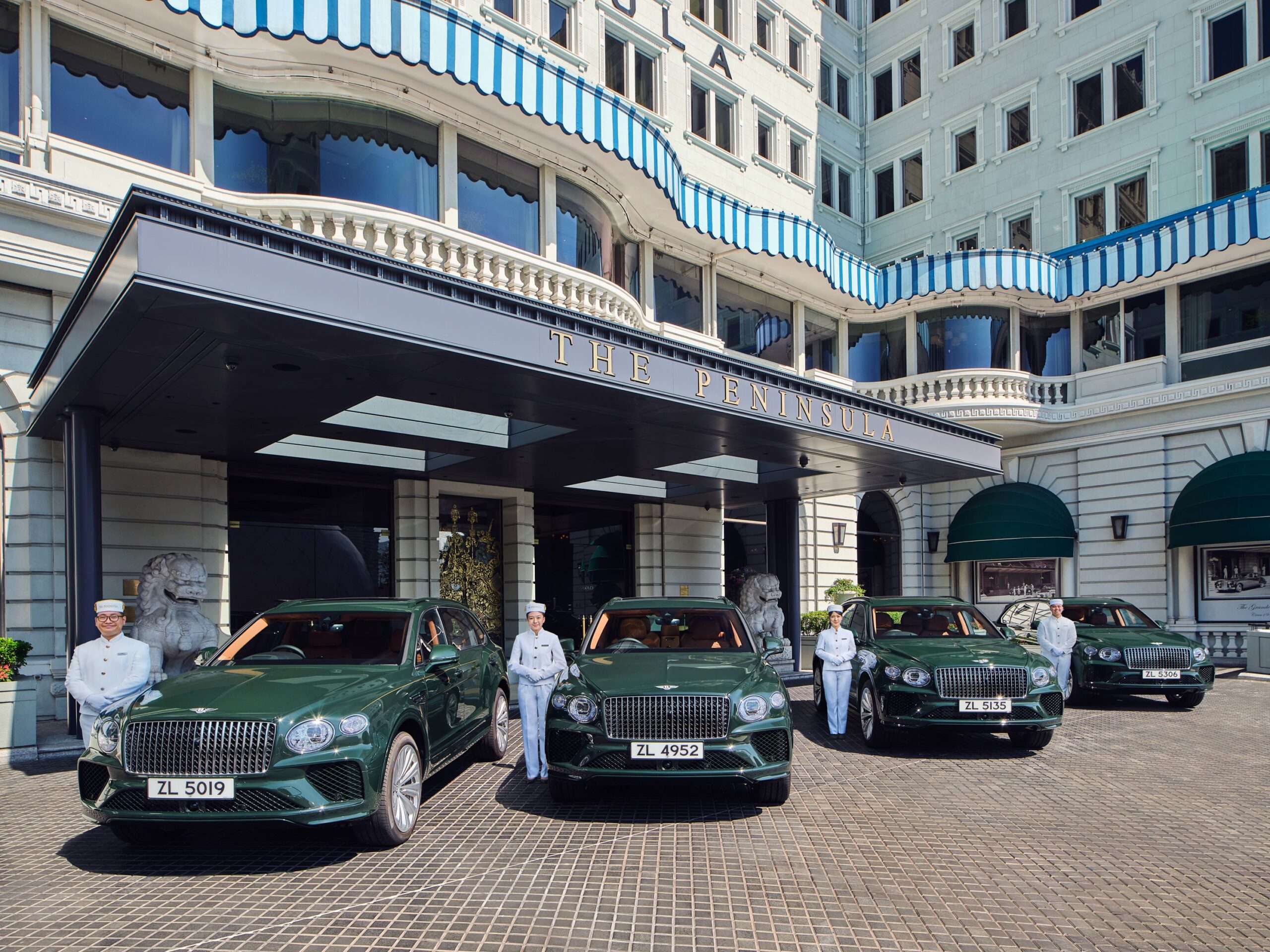 Four dark green Bentley Bentayga EWBs parked in front of The Peninsula Hong Kong.