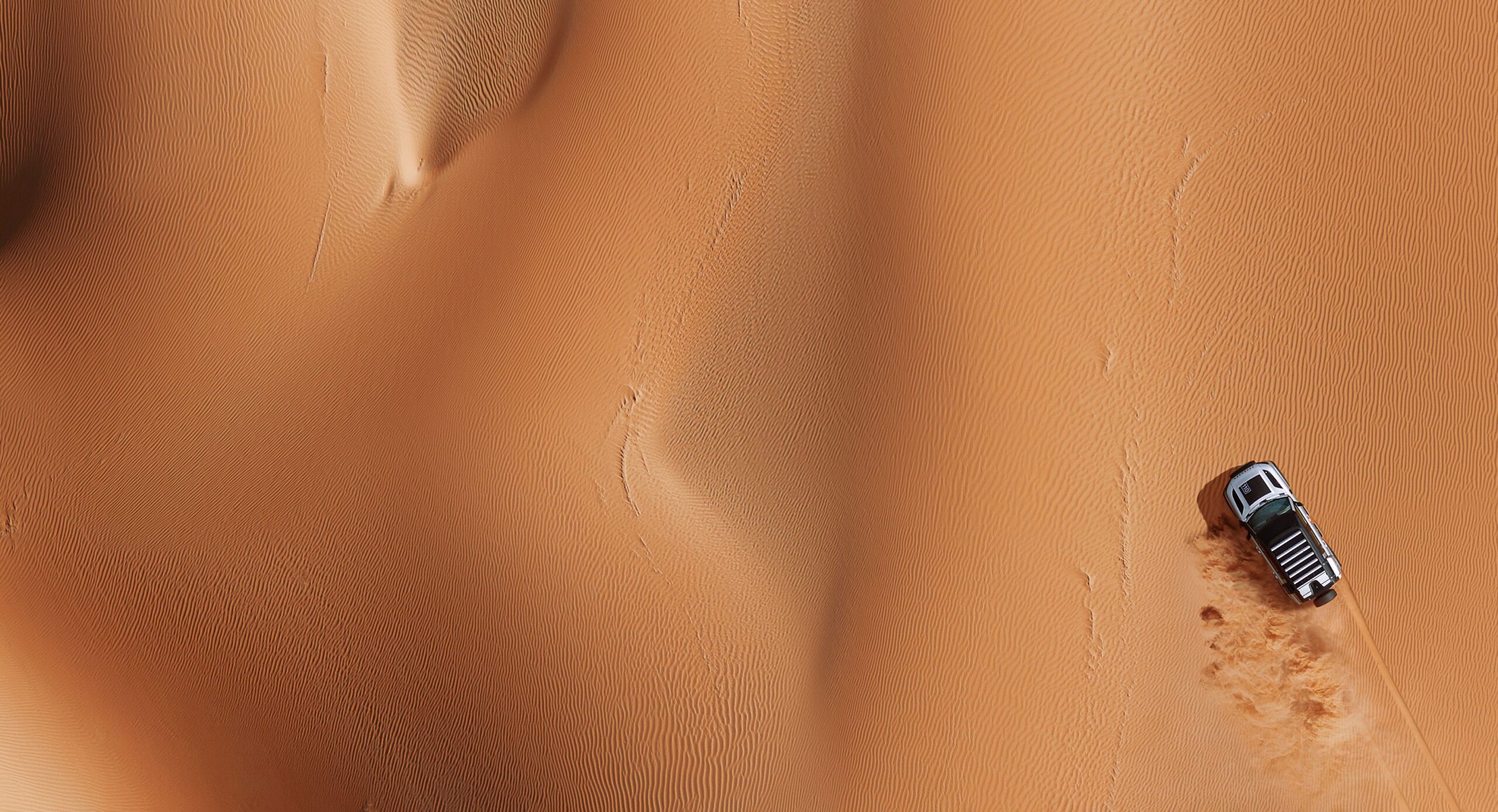 A Land Rover Defender driving over a desert.