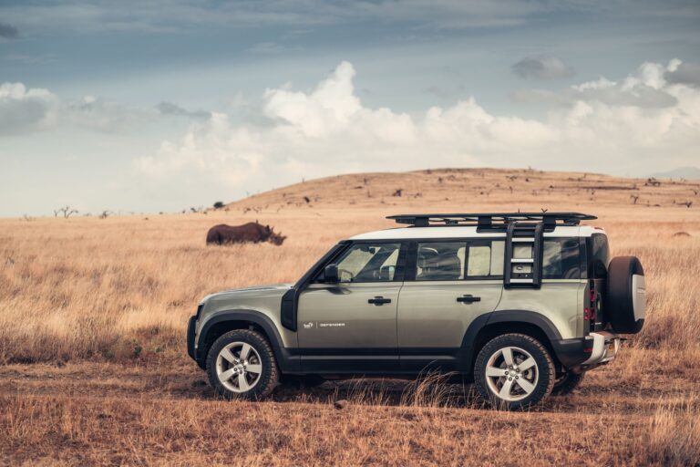 A Tusk branded Land Rover Defender 110 with a Rhinoceros in the background.