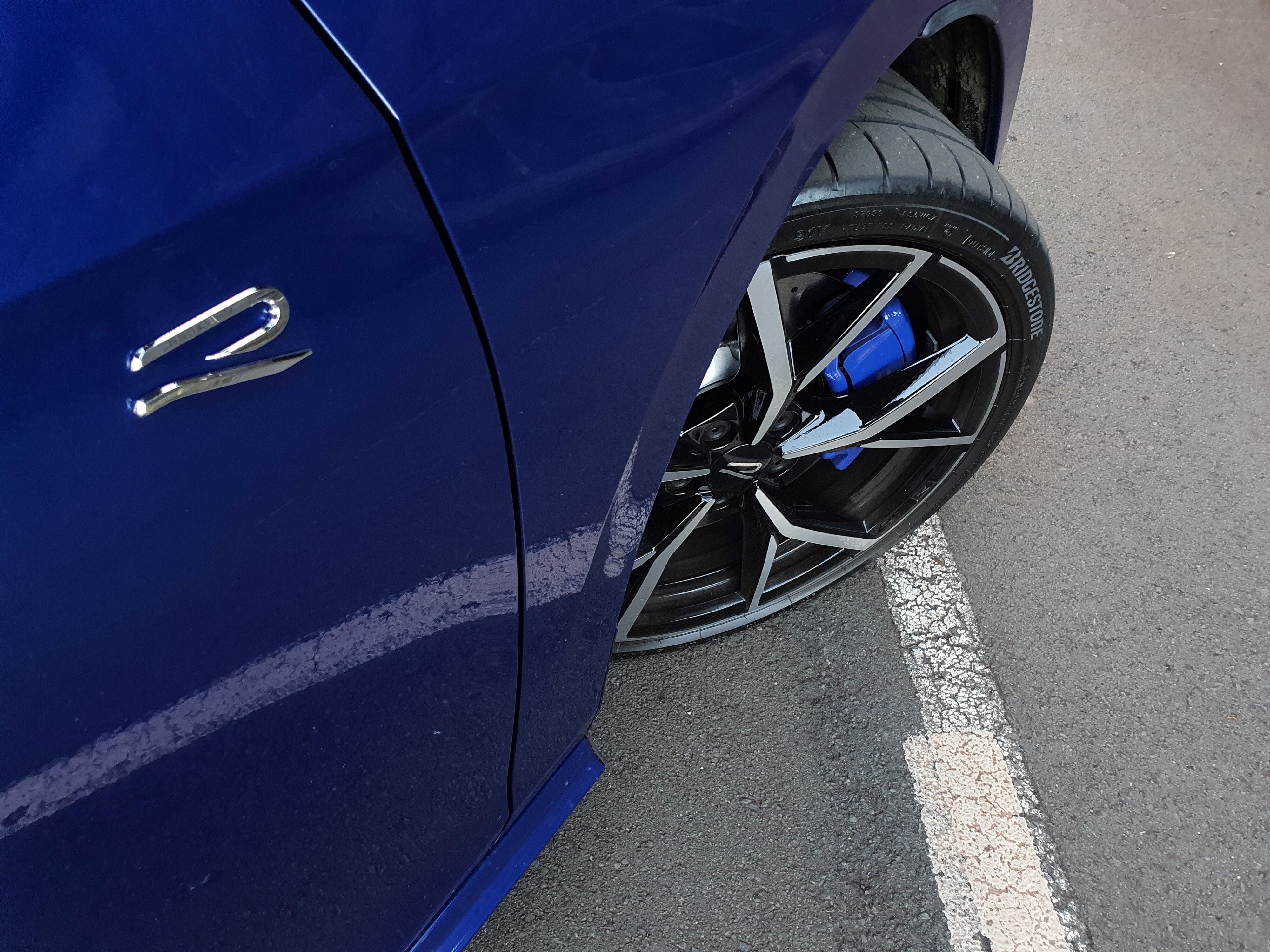 View of the R badging on the front right door of a 2025 Volkswagen Golf R Mk8.5 in Lapiz Blue Metallic.