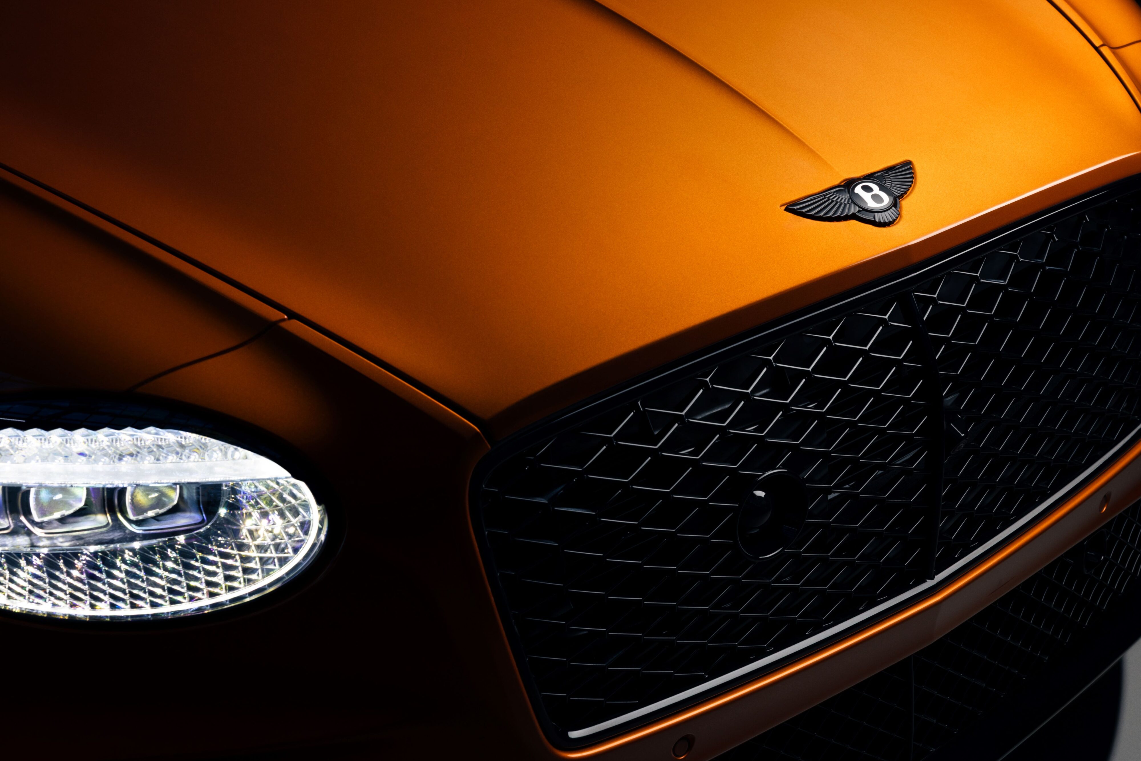 Front view of the nose of a Bentley Continental GTC Black Edition in Mandarin Orange with black 'Bentley Wings' on the nose.