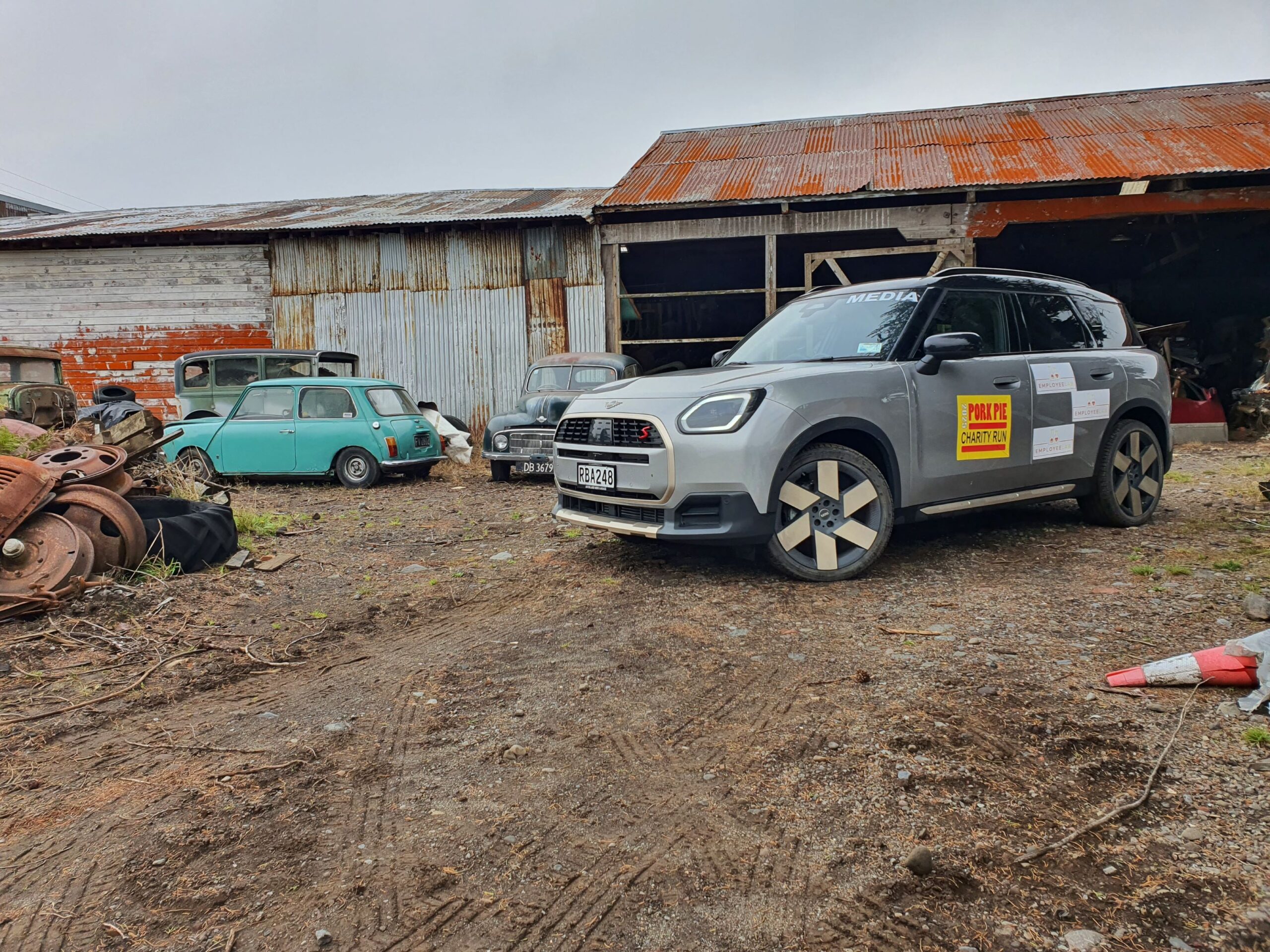Front three quarters view of a 2025 Mini Countryman S with Employee Lab branding in Smash Palace, Horopito on the 2025 Pork Pie Charity Run. A green classic Mini is visible in the background.