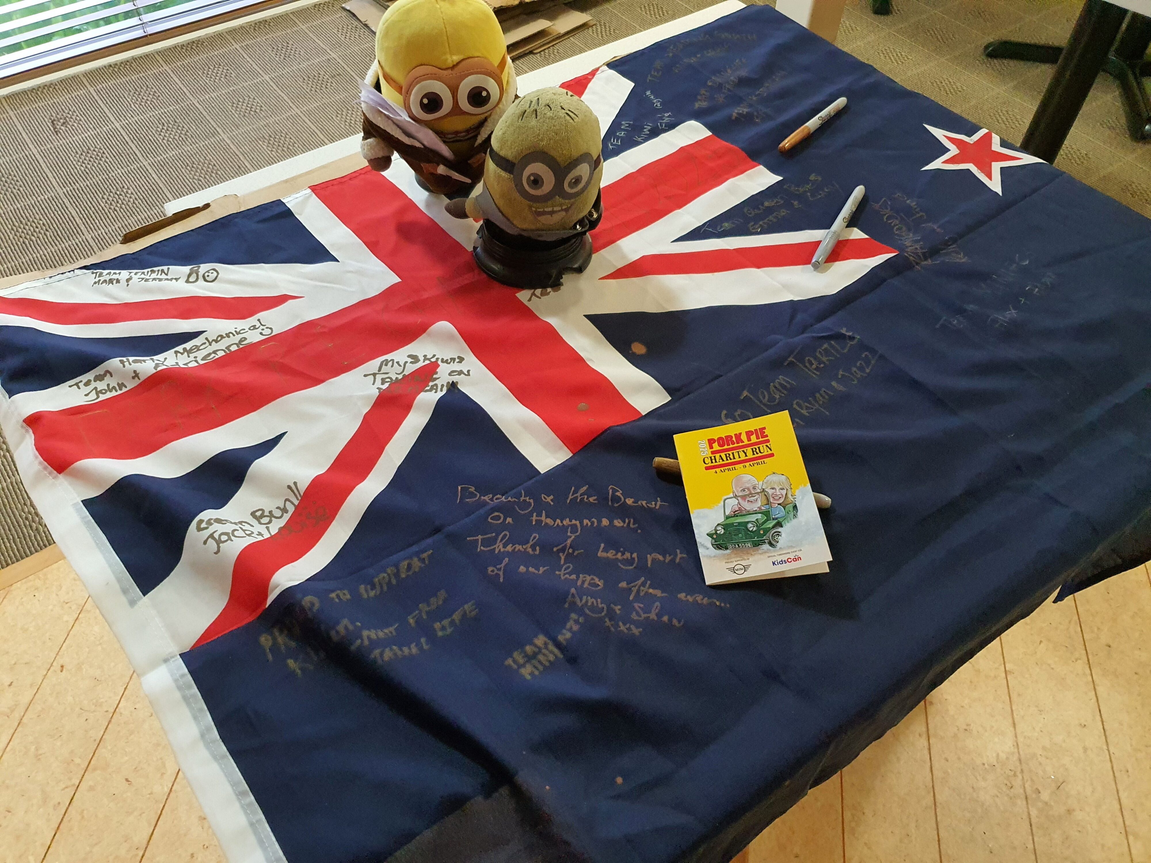 A signed New Zealand flag and 2025 Pork Pie passport from the 2025 Pork Pie Charity Run.