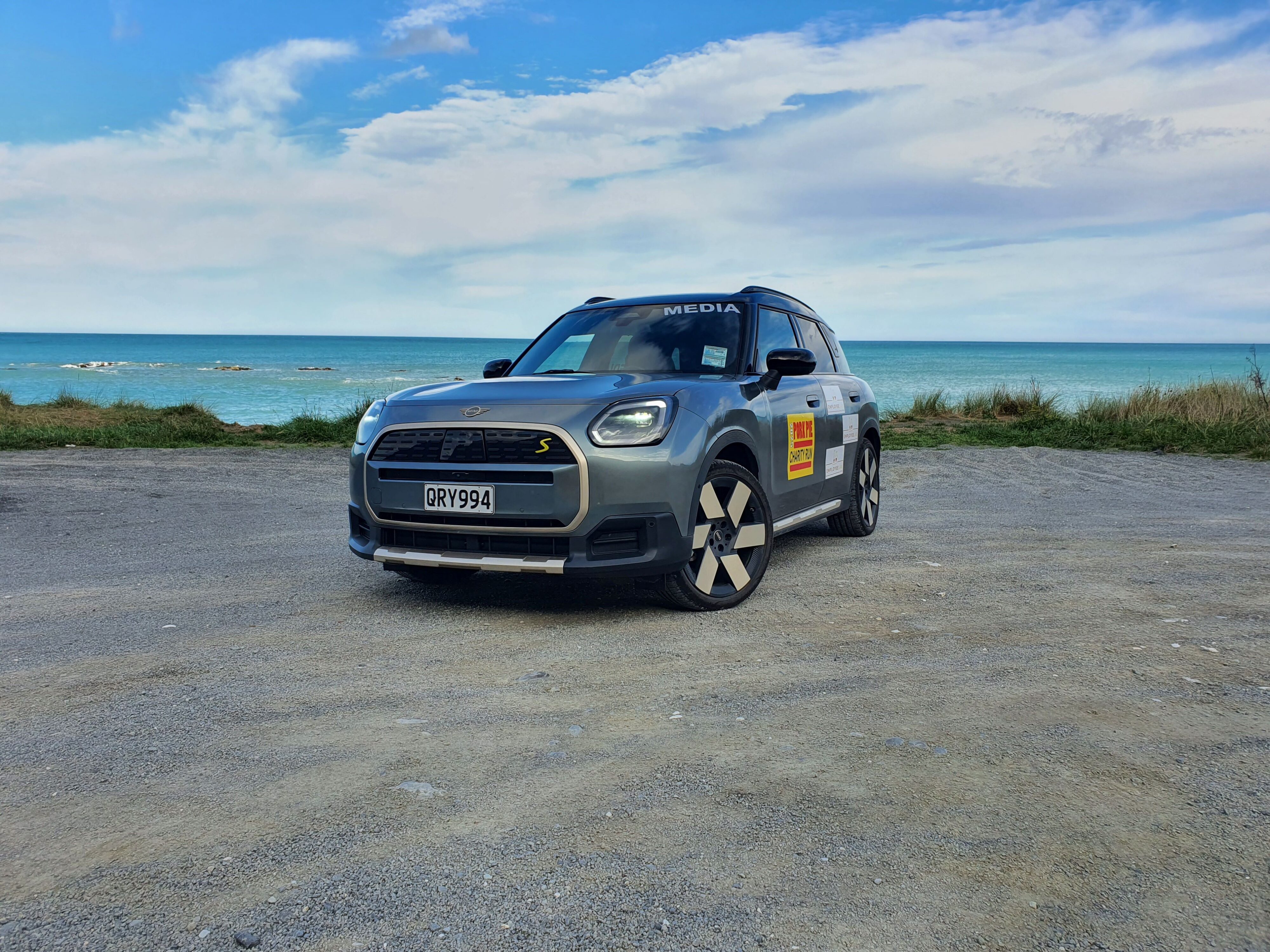 A 2025 Mini Countryman SE All4 with Mortgage Lab branding and the ocean in the background, taken just outside Kaikoura on the 2025 Pork Pie Charity Run.