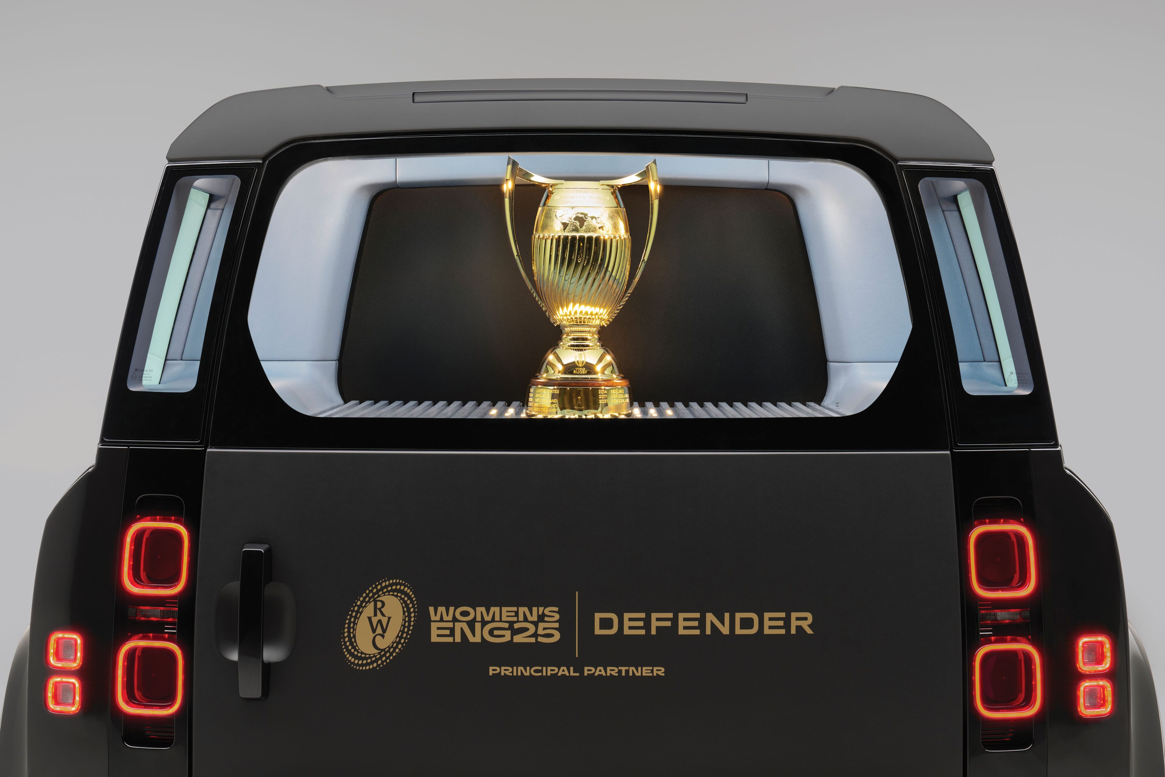 The 2025 Women's Rugby World Cup trophy presented in the back of a custom made Defender 110.