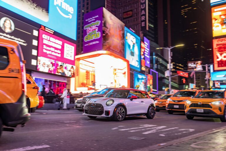 A photo of a white Mini John Cooper Works hatchback in Times Square, New York City.