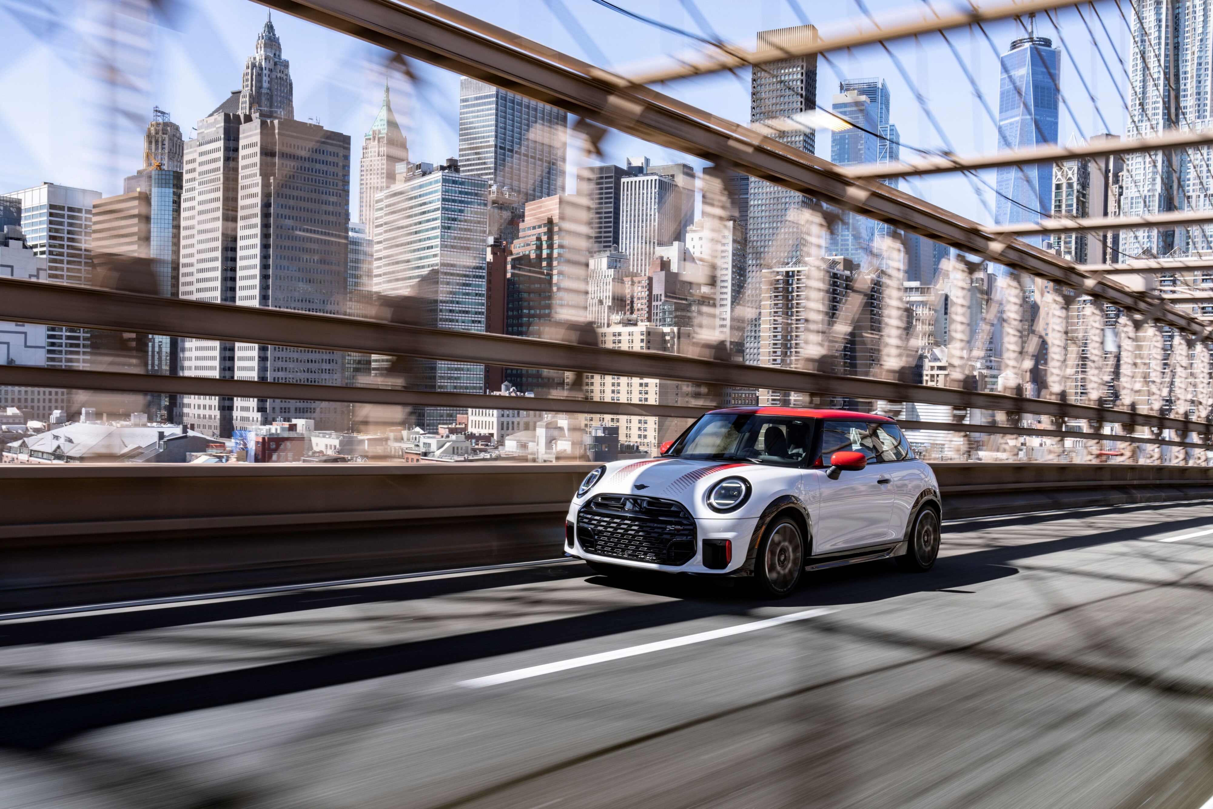 A photo of white on Chilli Red Mini John Cooper Works hatchback on Brooklyn Bridge in New York.