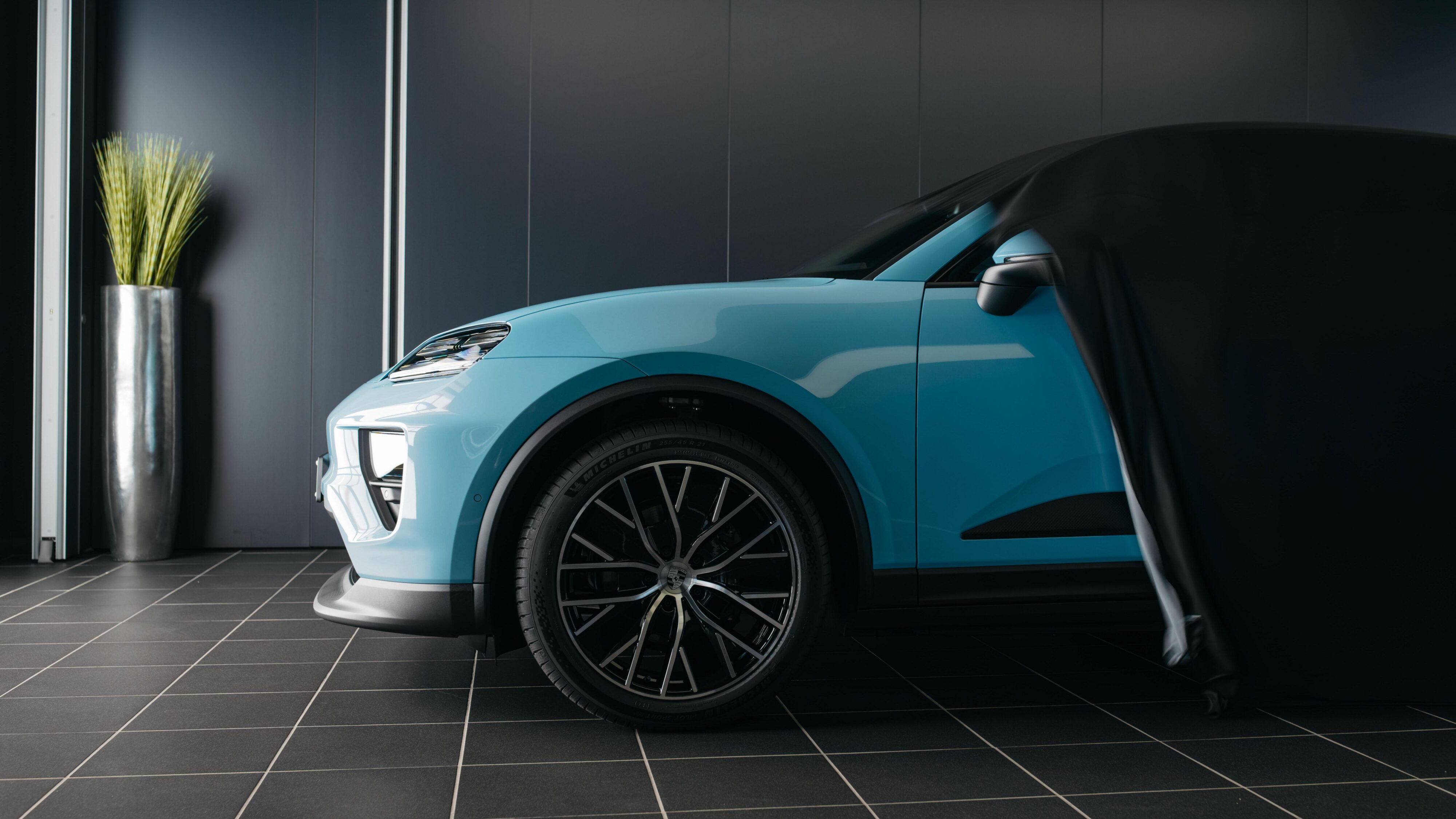 Side on view of a baby blue Porsche Macan 4S with its car cover half off.