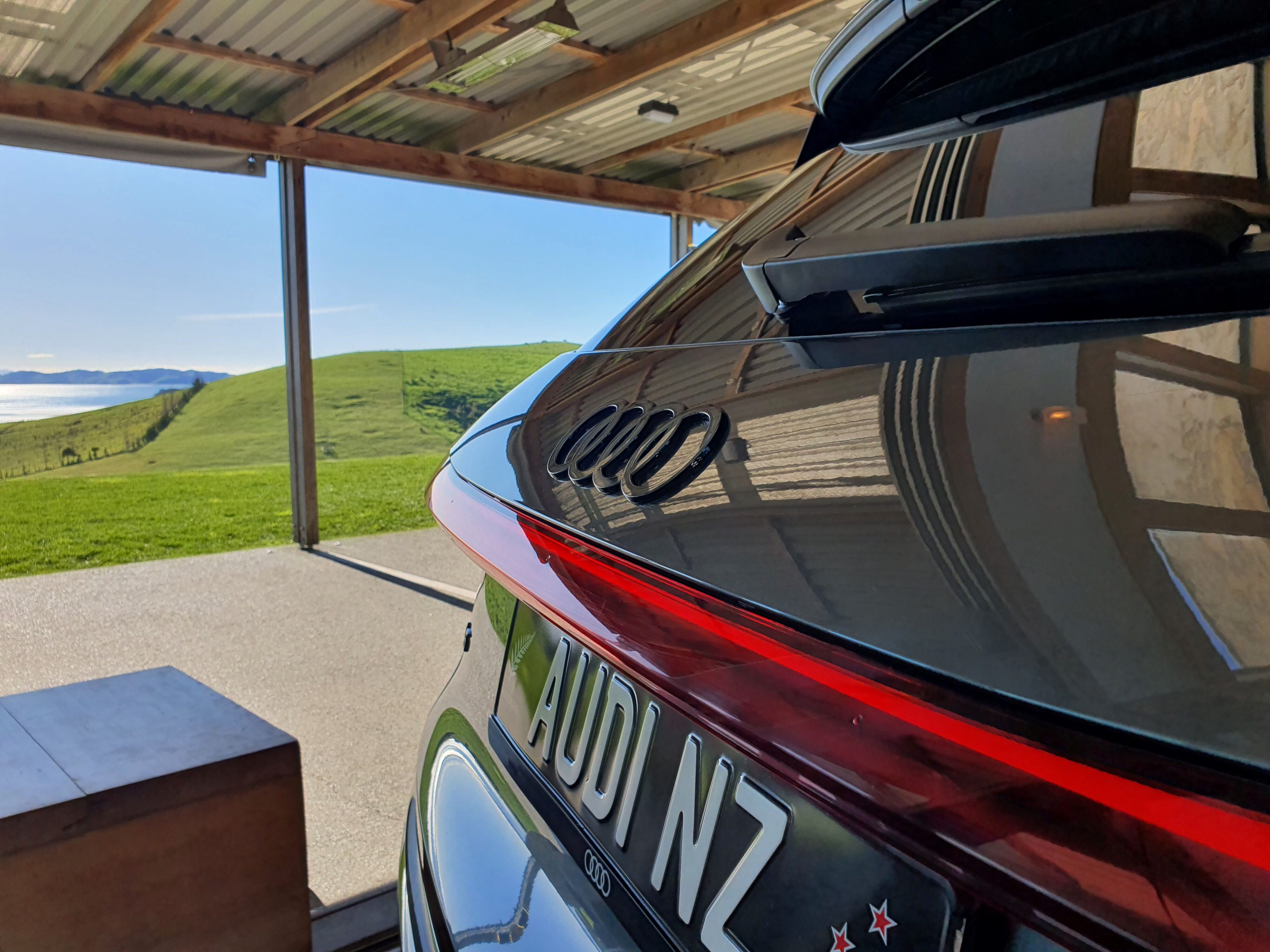 Rear view of a 2025 Audi SQ5 with an outlook of Kauri Bay in the background.