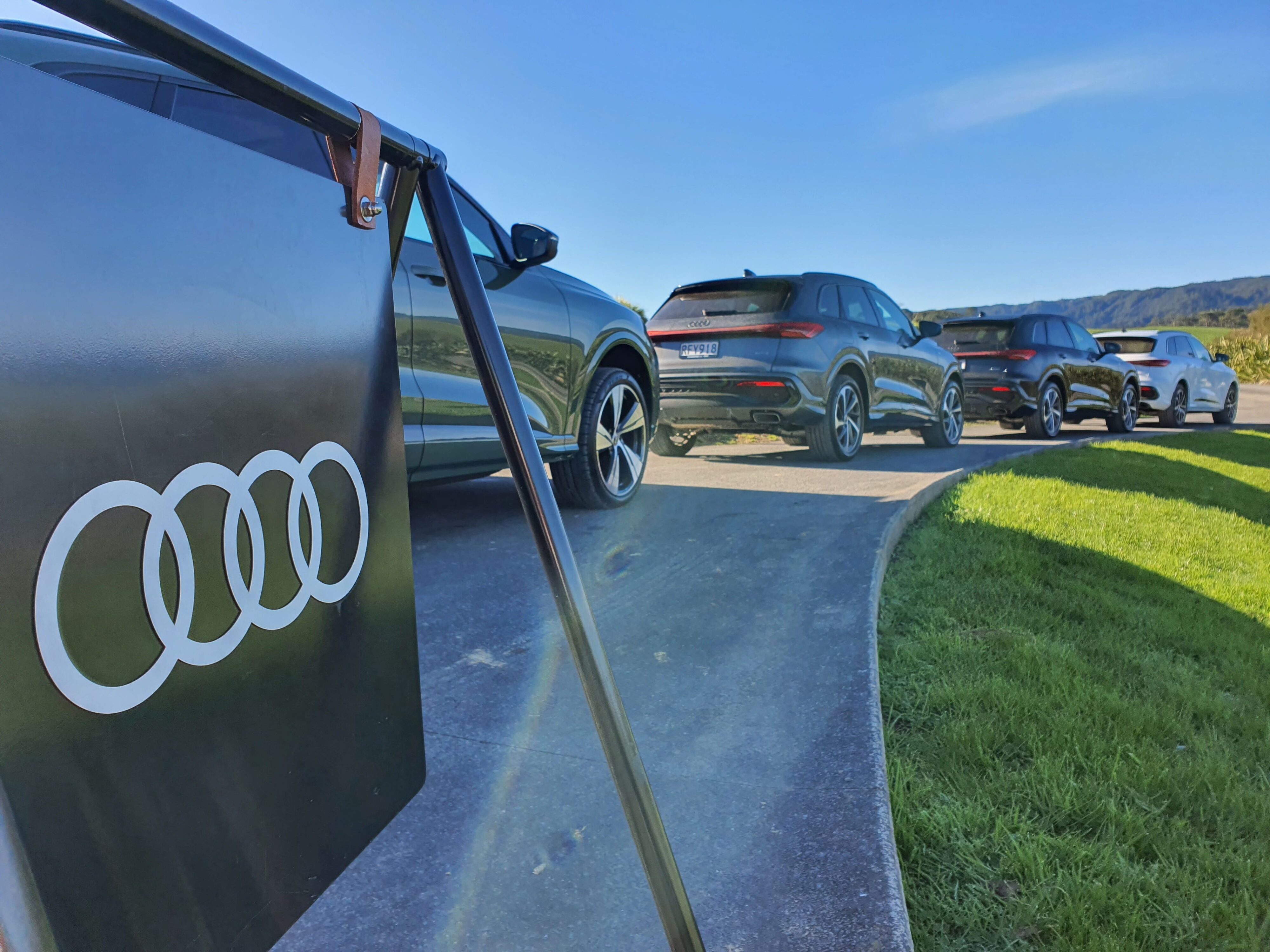 A view of the Audi logo with a lineup of new Audi Q5s and SQ5s in the background.