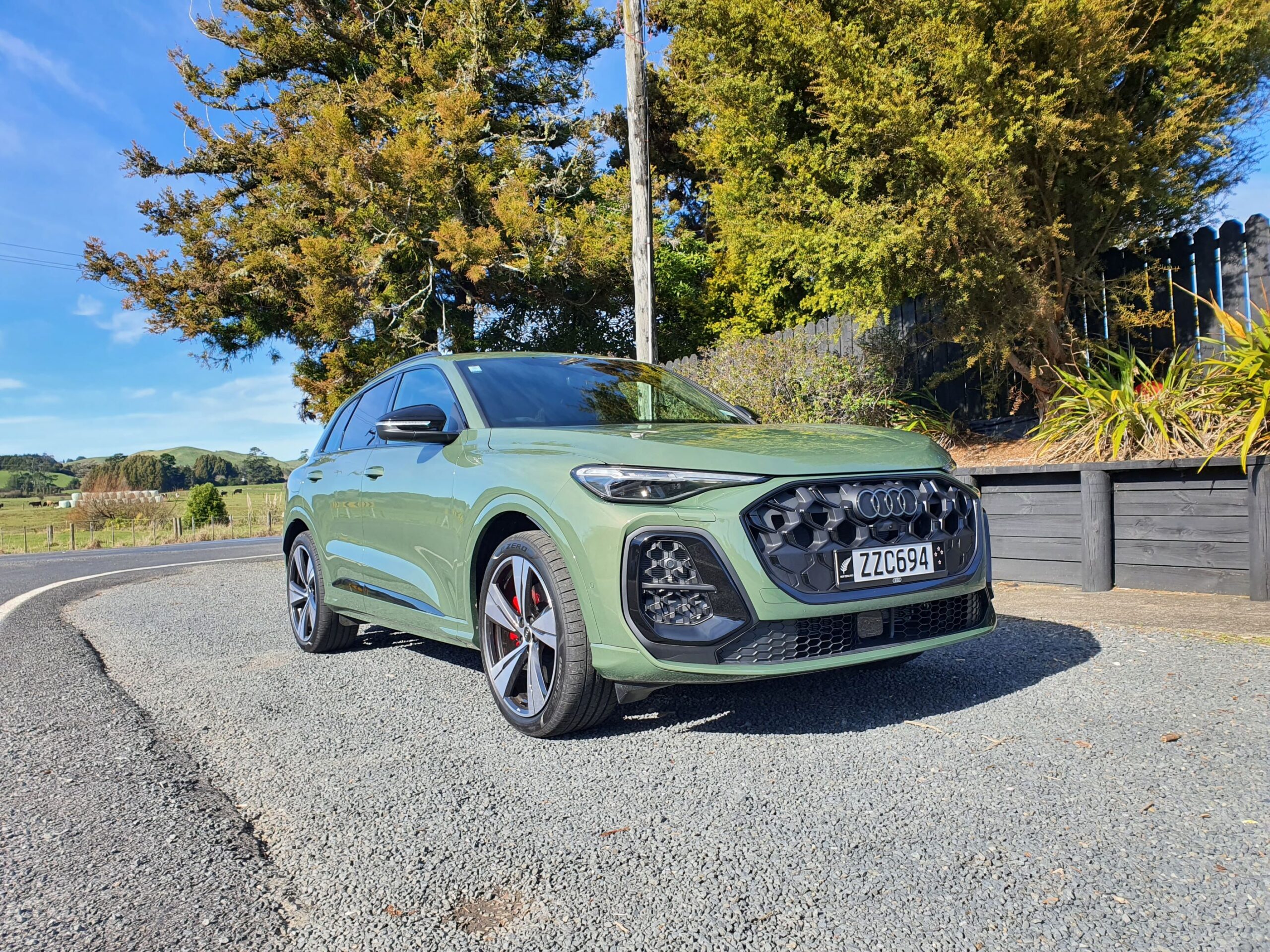 Front three quarters view of a 2025 Audi SQ5 in District Green, taken at Kauri Bay, Auckland.