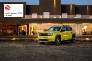 A photo of a mustard colour Fiat Grande Panda with a Red Dot Design Award banner at the top left.