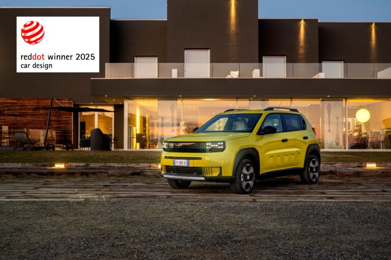 A photo of a mustard colour Fiat Grande Panda with a Red Dot Design Award banner at the top left.