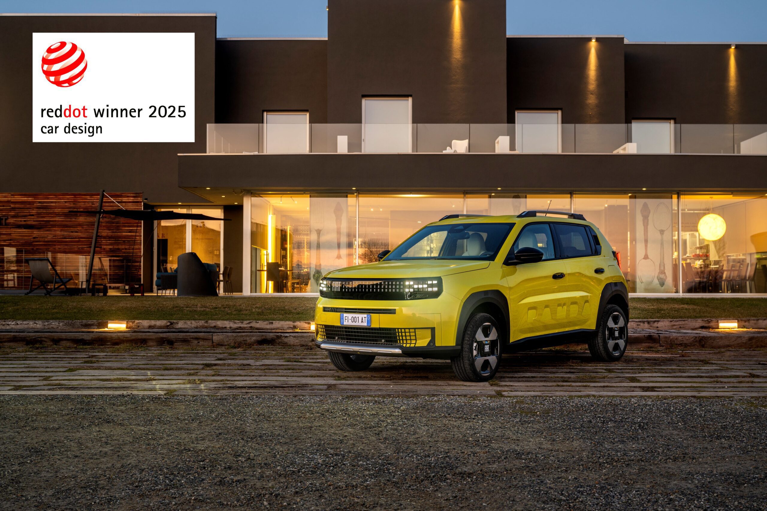 A photo of a mustard colour Fiat Grande Panda with a Red Dot Design Award banner at the top left.