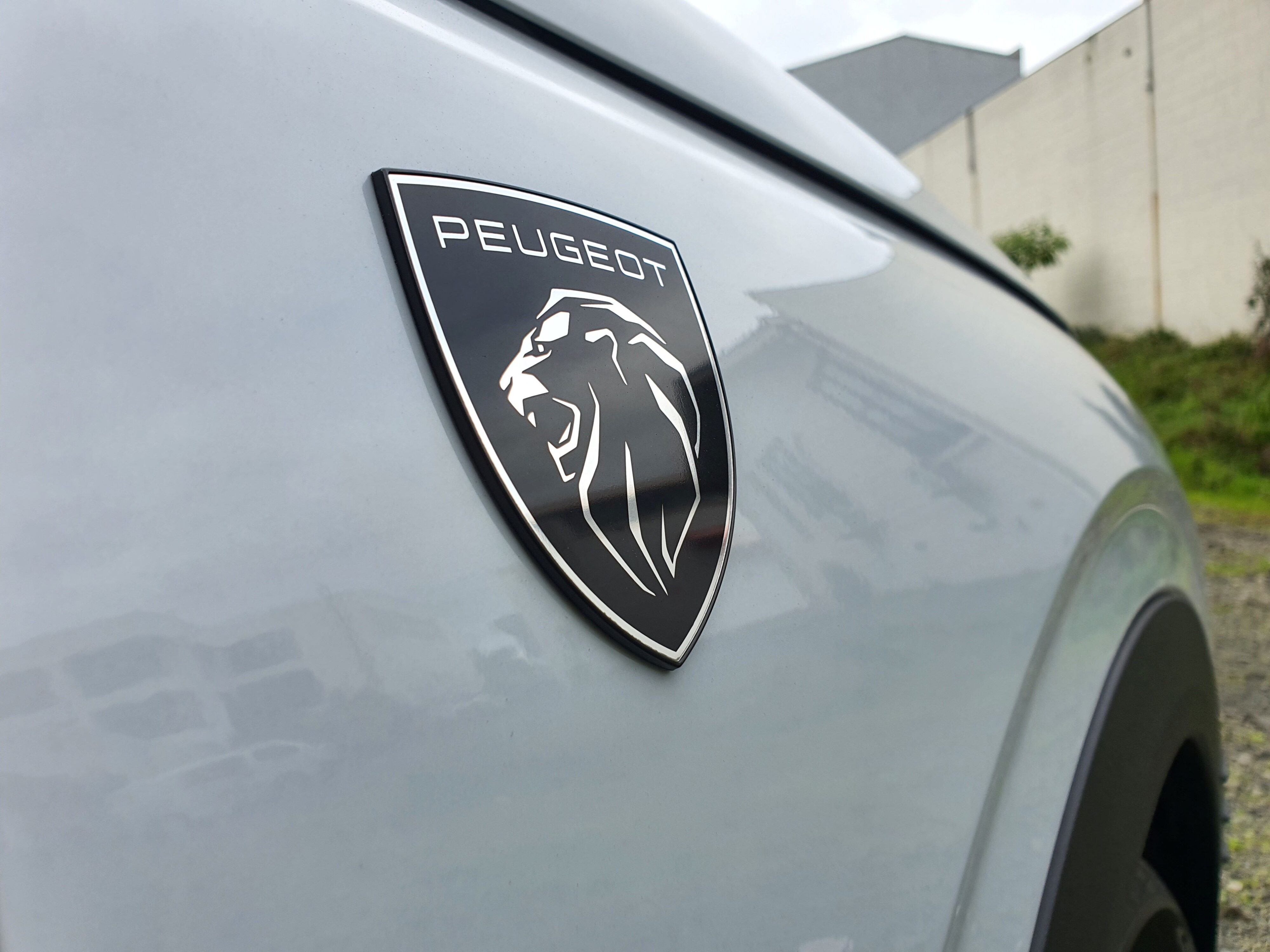 View of the Peugeot logo shield on the right front wheel arch of a 2025 5008 Hybrid.