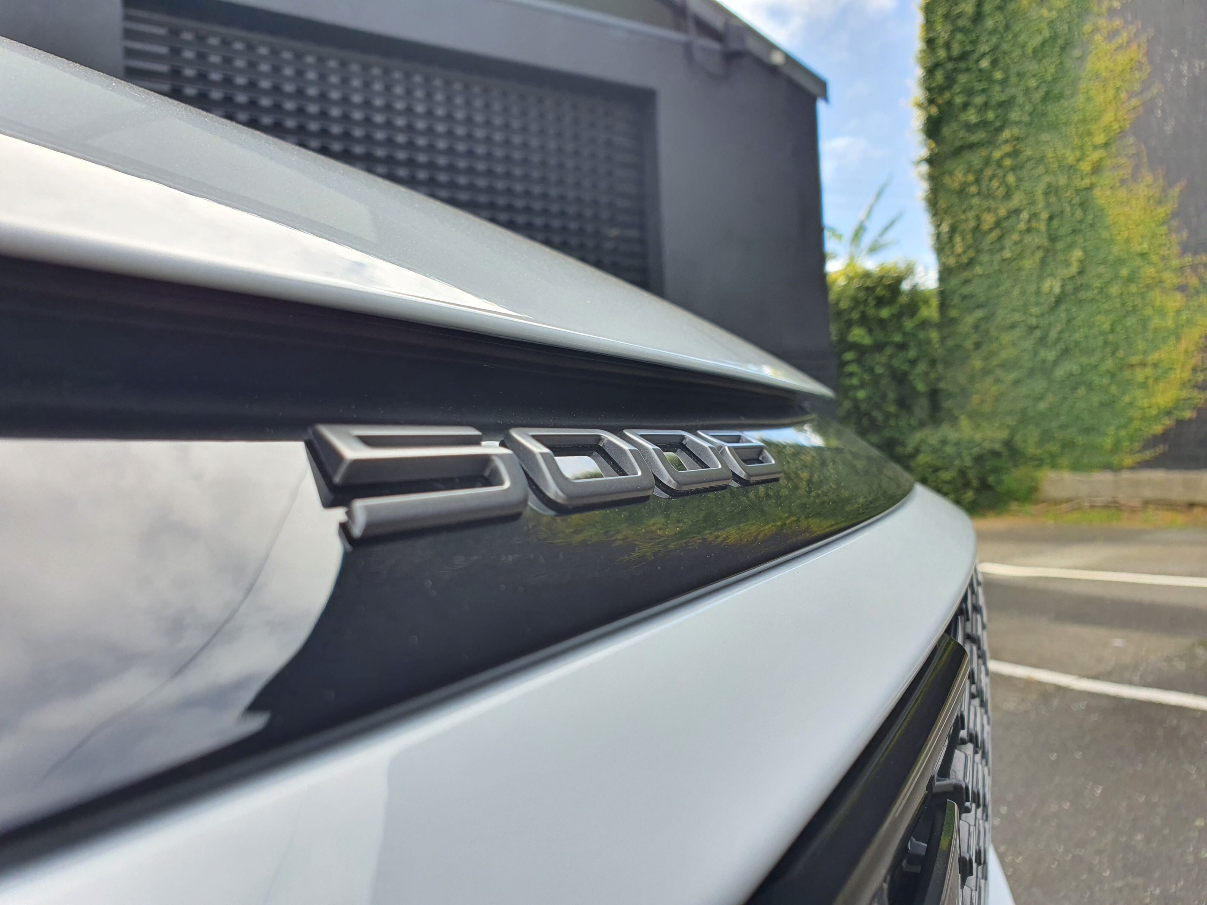 '5008' badging on the nose of a 2025 Peugeot 5008 Hybrid in Okenite White and Diamond Black.