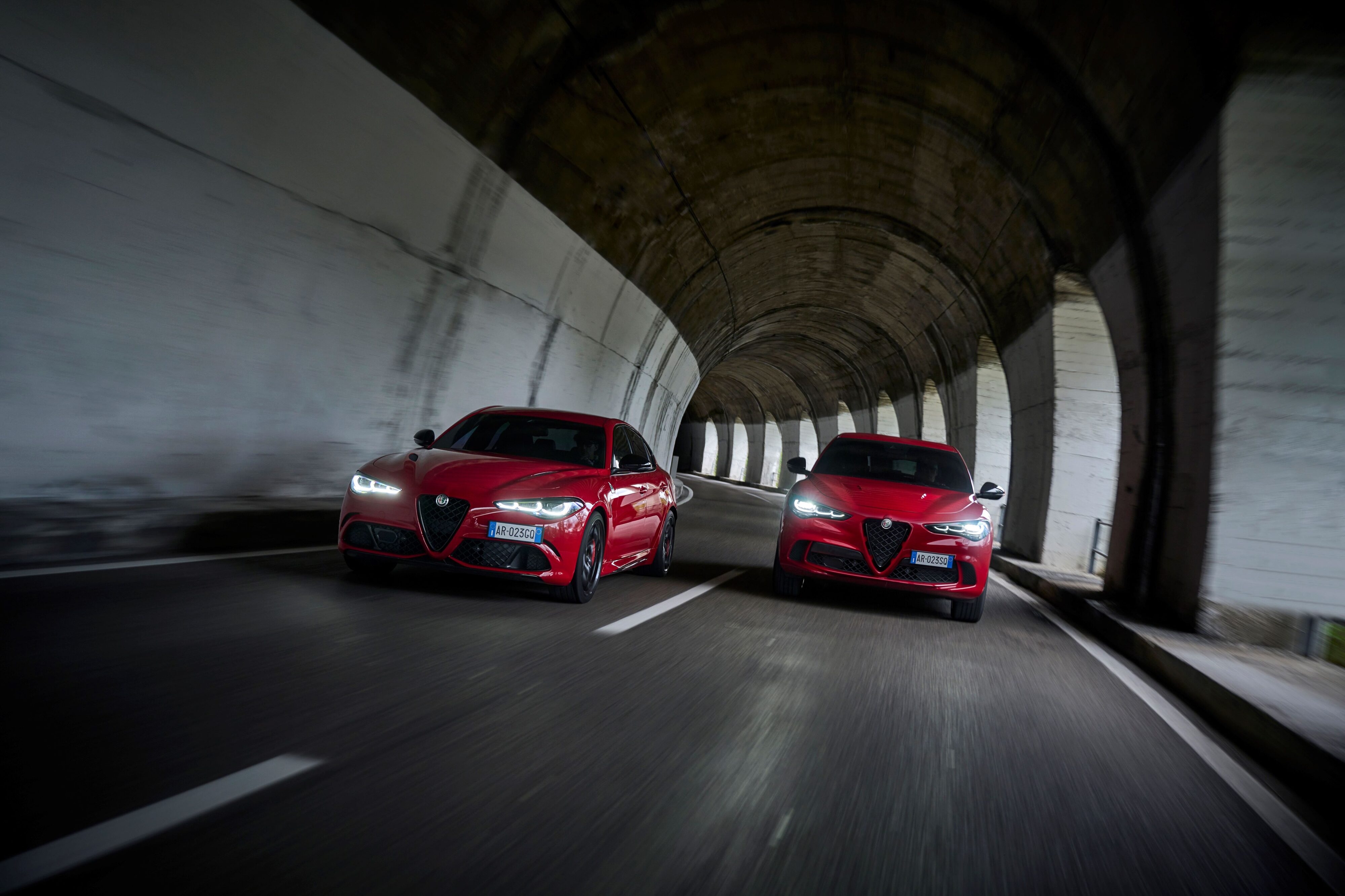 A photo of an Alfa Romeo Giulia Quadrifoglio and Stelvio Quadrifoglio side by side in a tunnel, both in red.