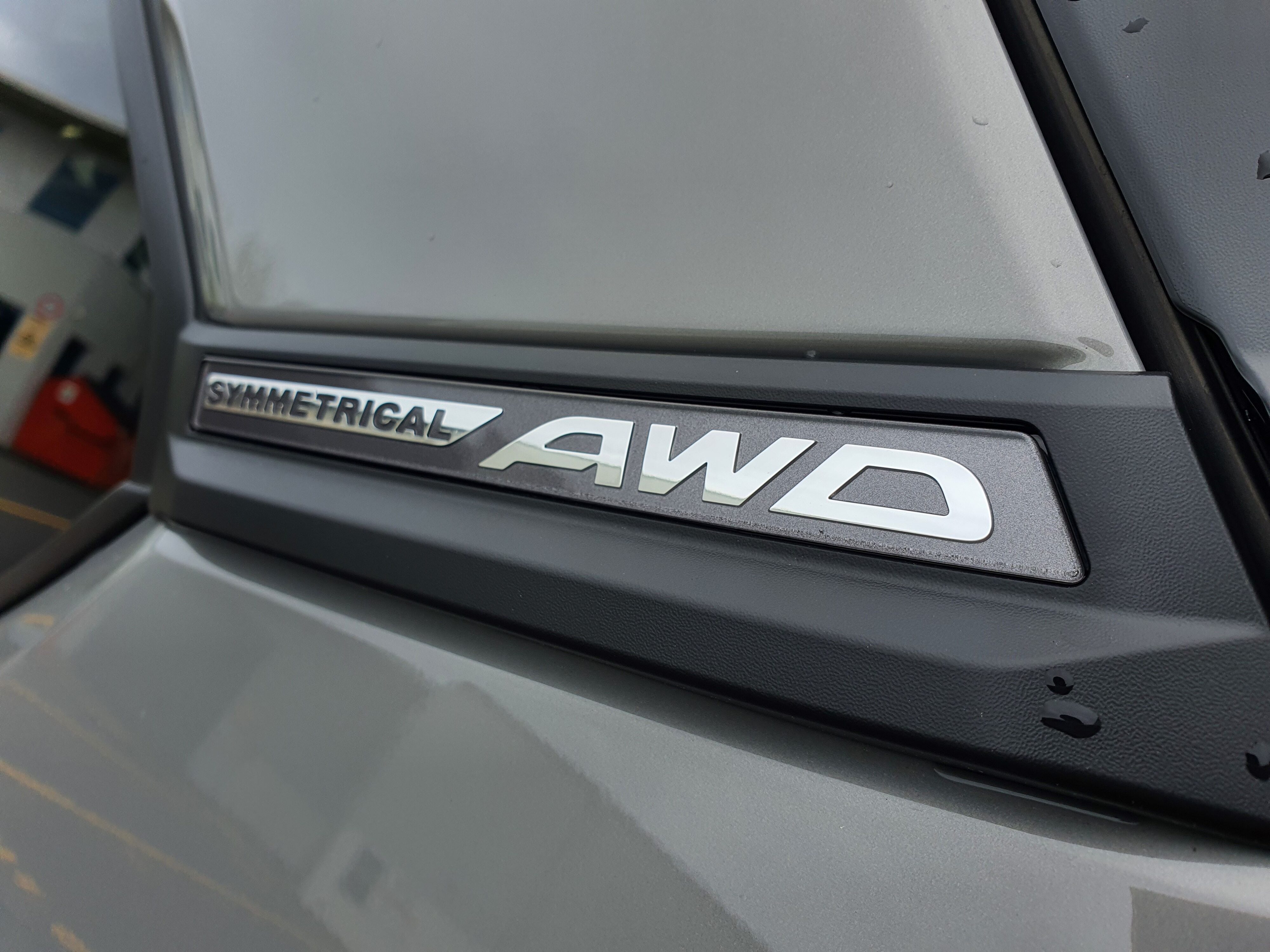 Close up the 'symmetrical AWD' badge on a 2025 Subaru Forester AWD Touring Hybrid in River Rock Pearl.