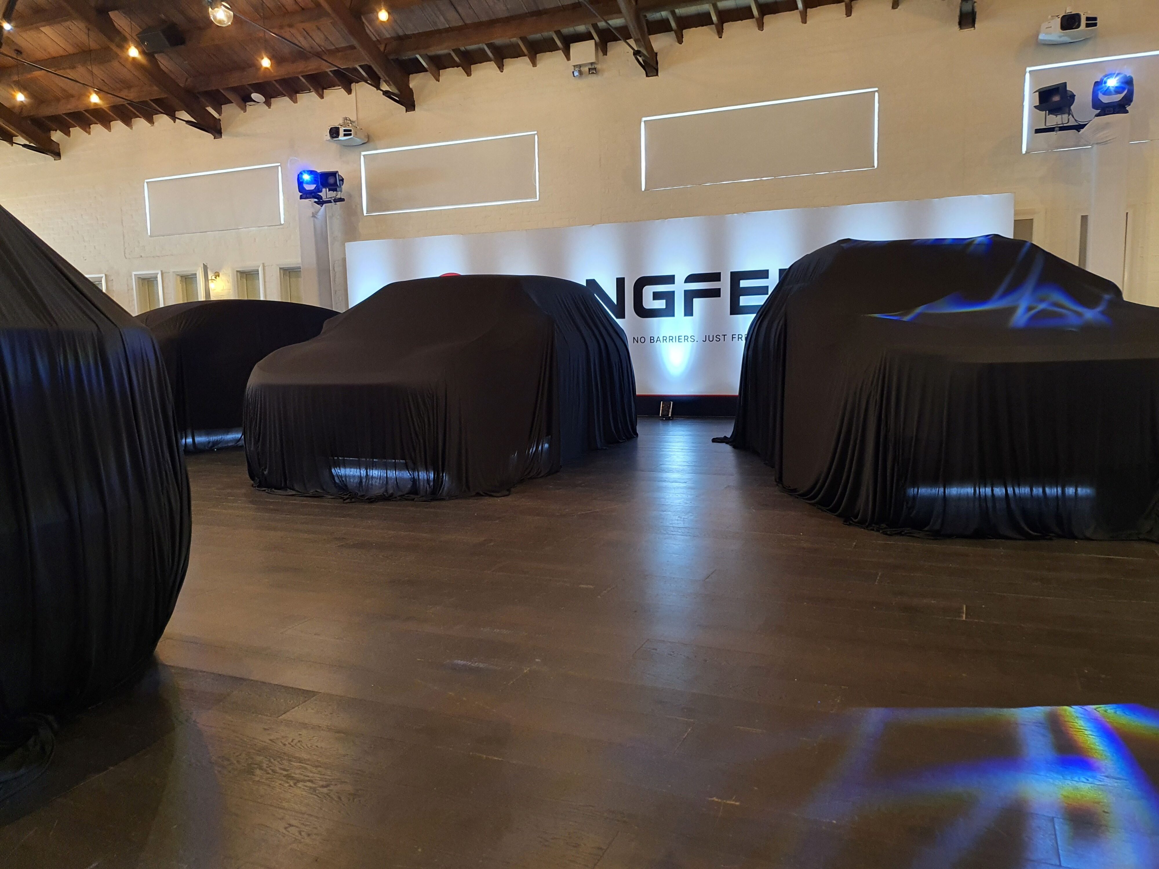 A photo of the three Dongfeng cars under covers at the 2025 New Zealand launch of the Dongfeng Motors brand and Box EV.