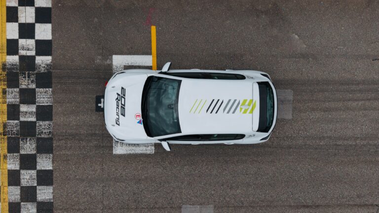 An overhead photo of a Peugeot 208 Racing TC6 on the starting grid of a racetrack.